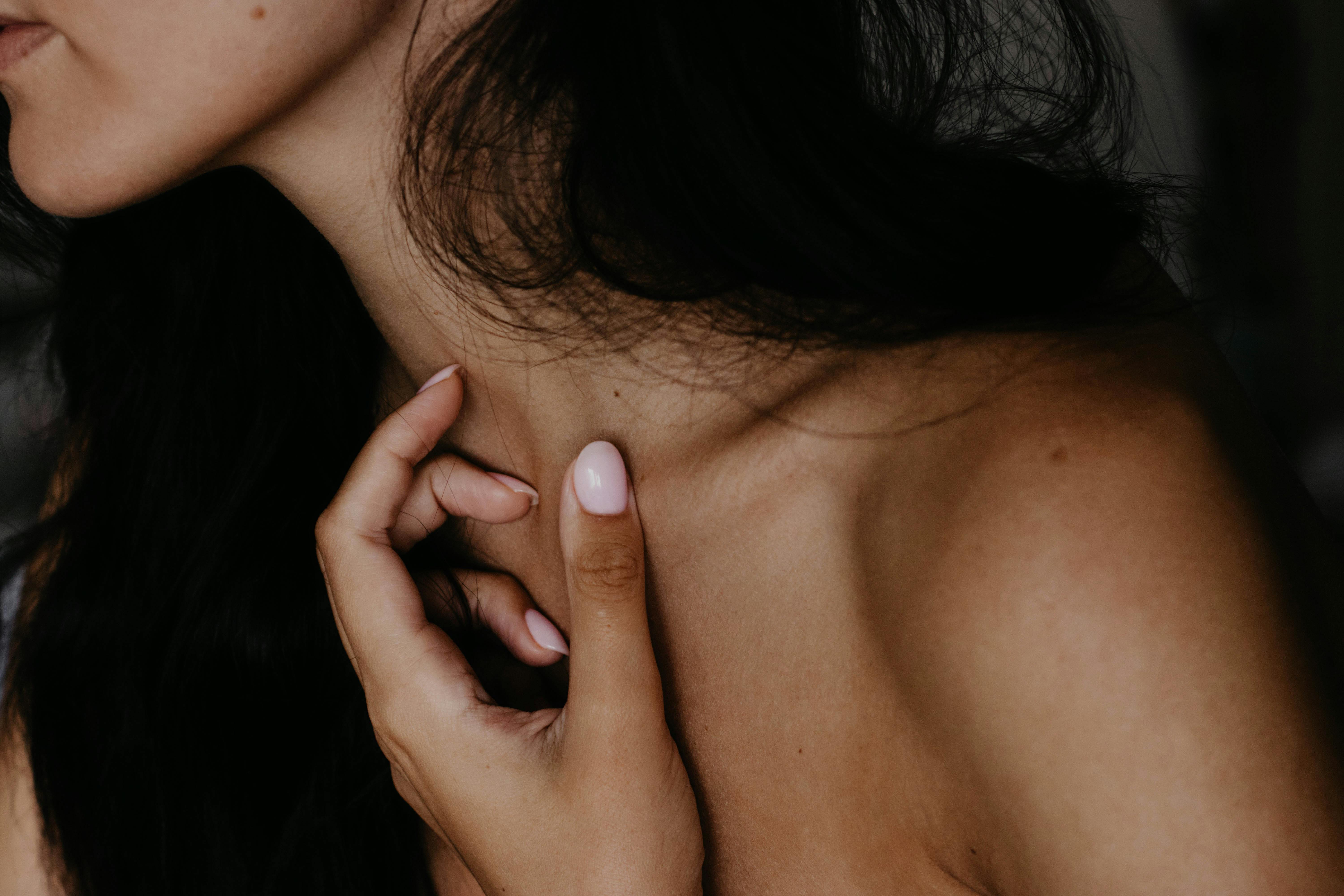 A woman seems to be reconnecting gently with her body, gently touching her neck with her hand and caressing her skin