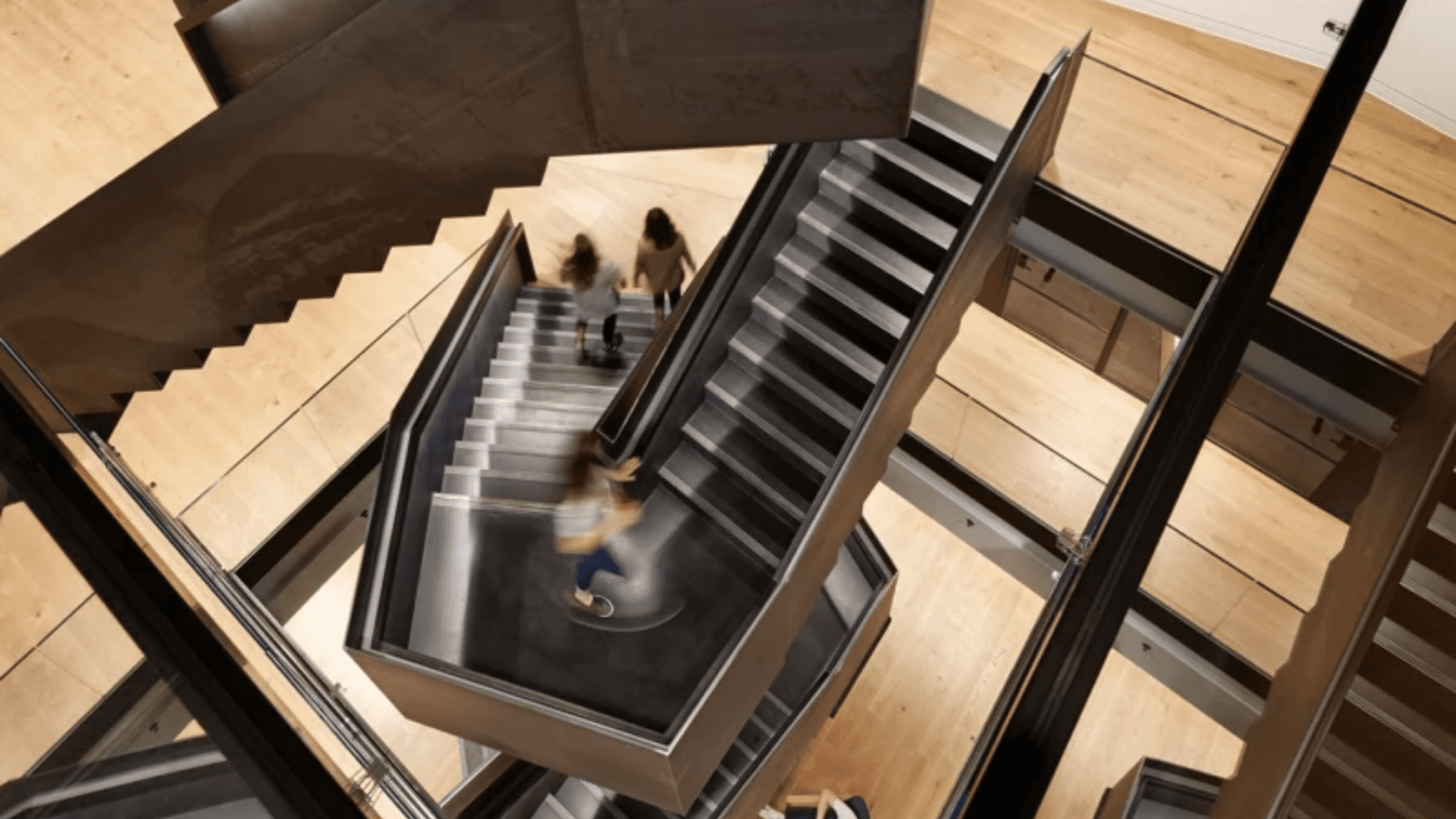 A spiraling staircase with a few blurred people walking up them