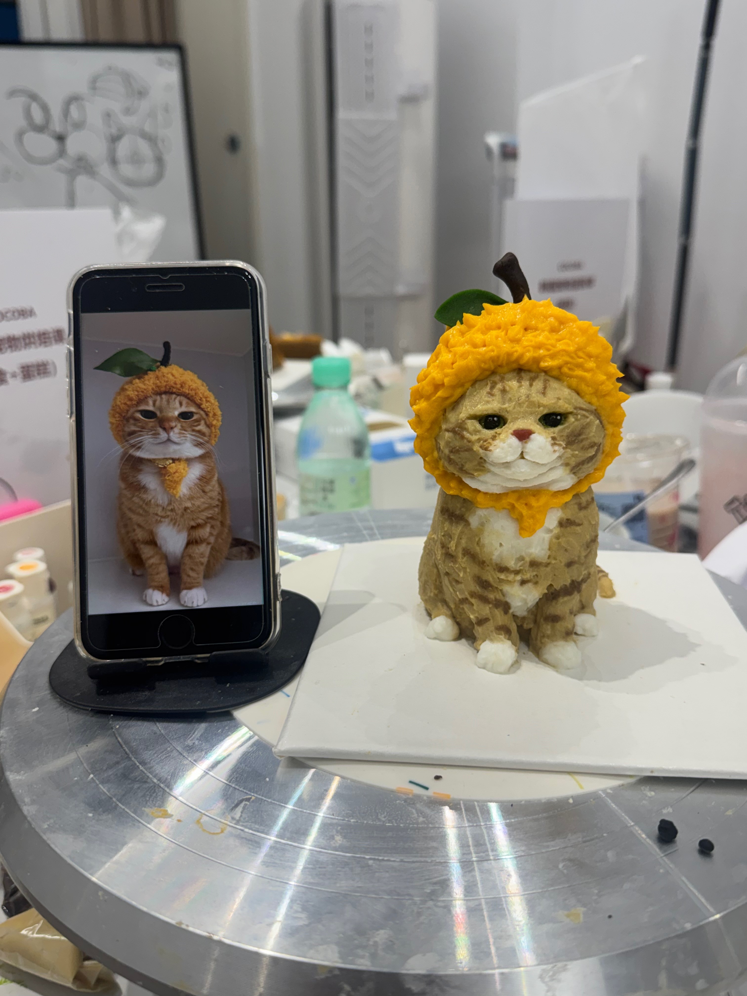 Cat reference photo beside a sculpted cat cake in progress