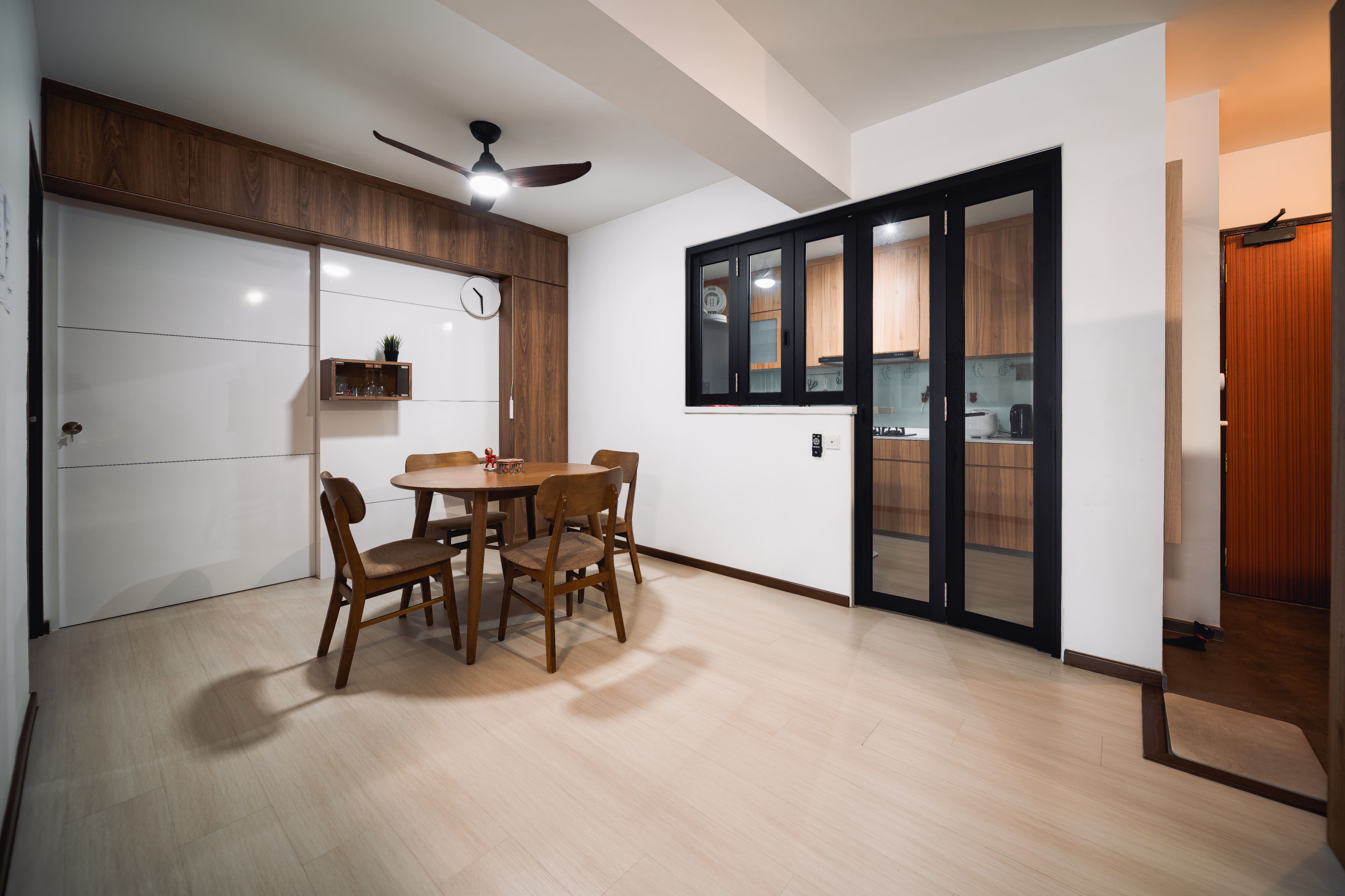 Dining nook featuring a wooden table, ceiling fan, and sliding cabinetry, paired with glass kitchen doors.