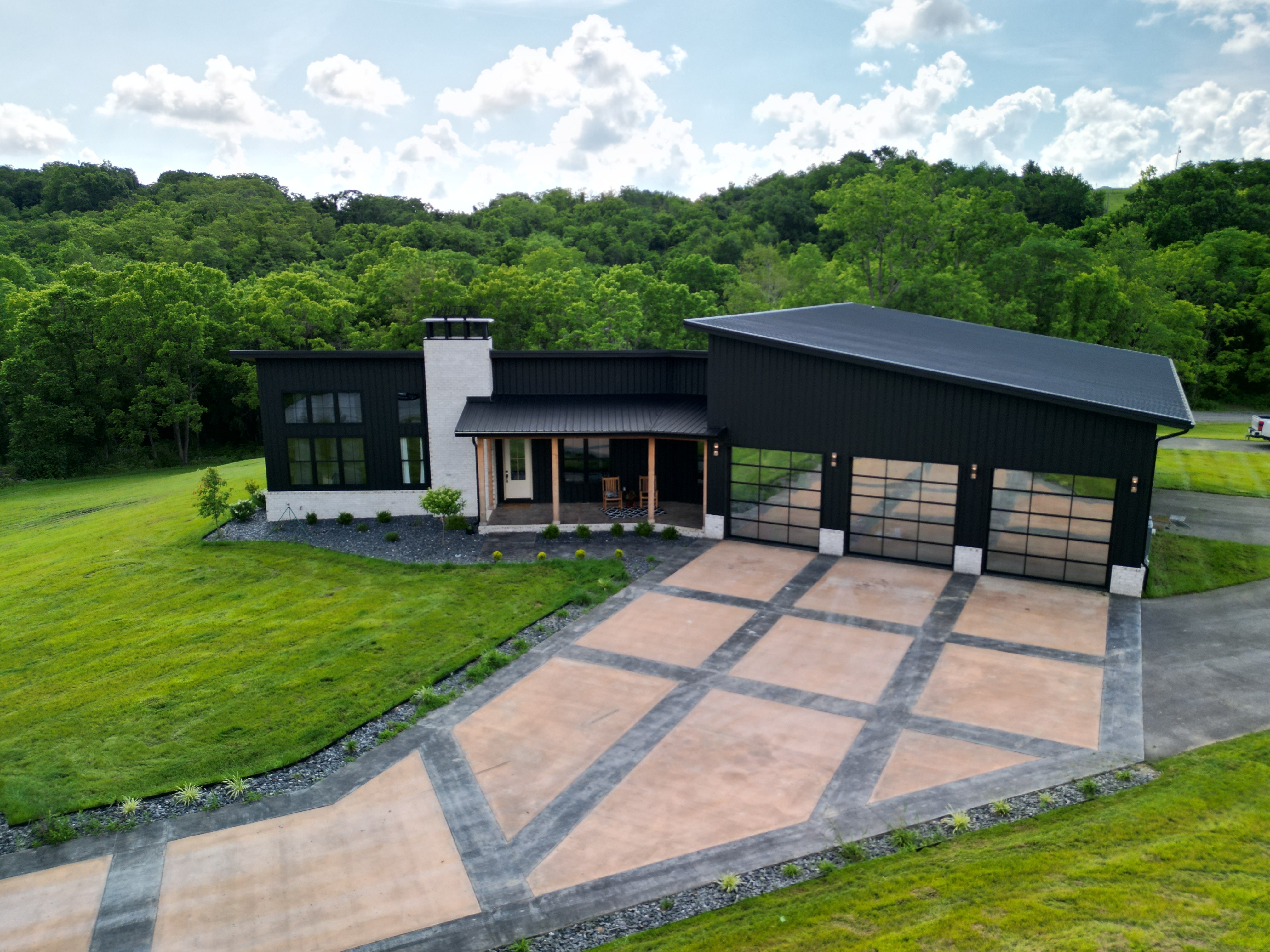 Modern indoor space with large glass doors, lush greenery, and a cozy seating area visible beyond.