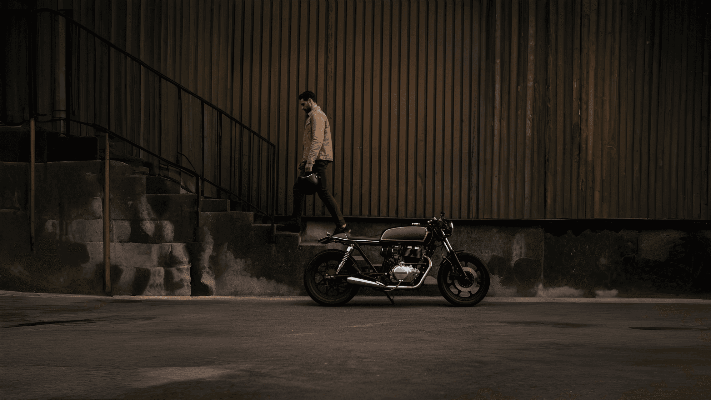 Man walking up the stairs with a motorcycle in front of him.