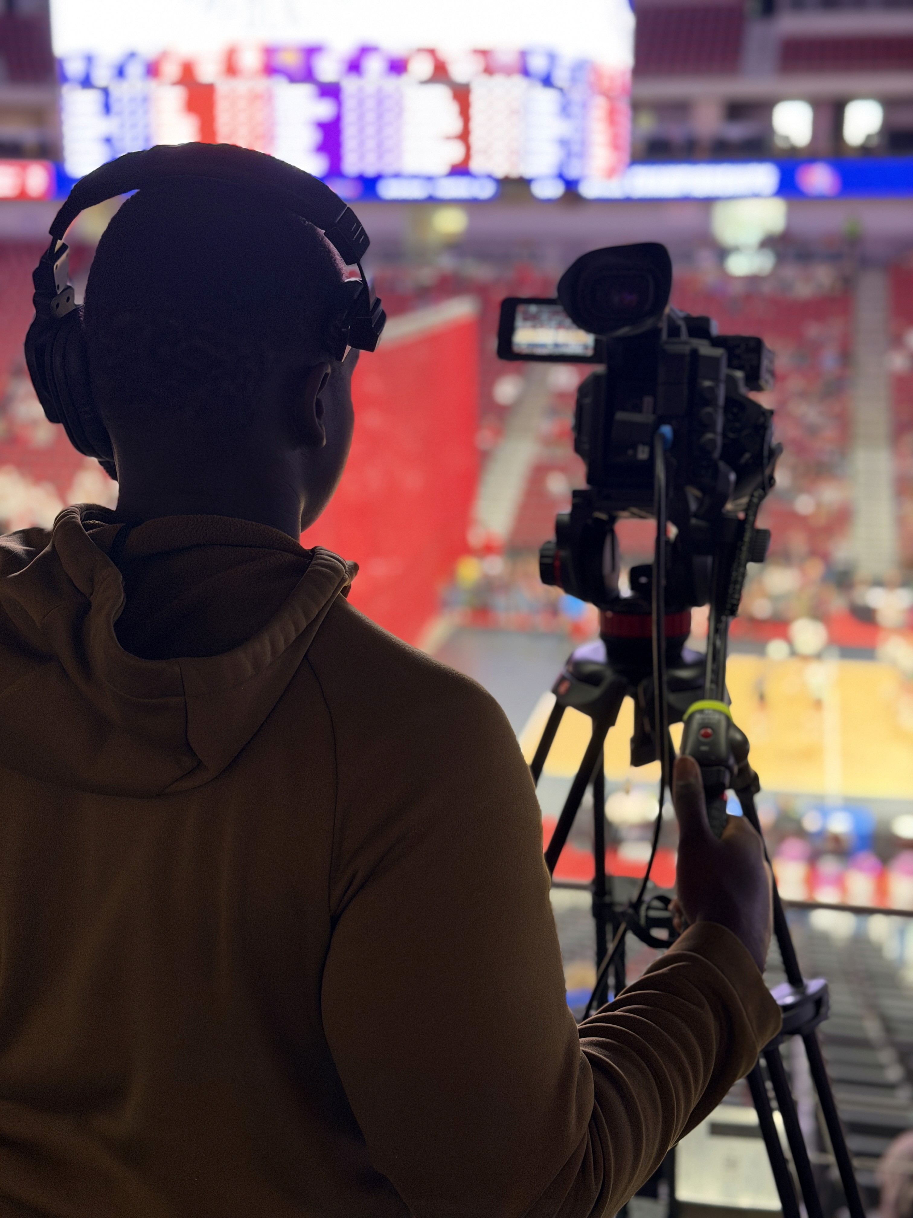 Student camera operator broadcasting a state basketball tournament from the upper deck of an arena