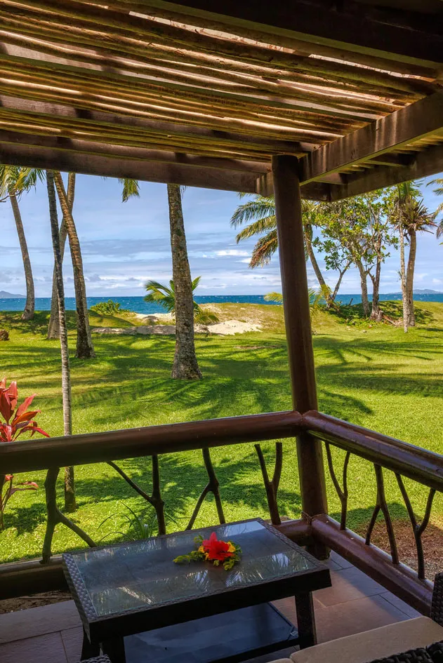 Balcony view at Uprising Beach Resort, a tropical Fiji beachfront resort, with palm trees and ocean beyond.