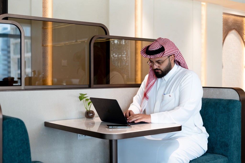 Remote work setup at TEC KSA with laptop and beverage in stylish coworking café