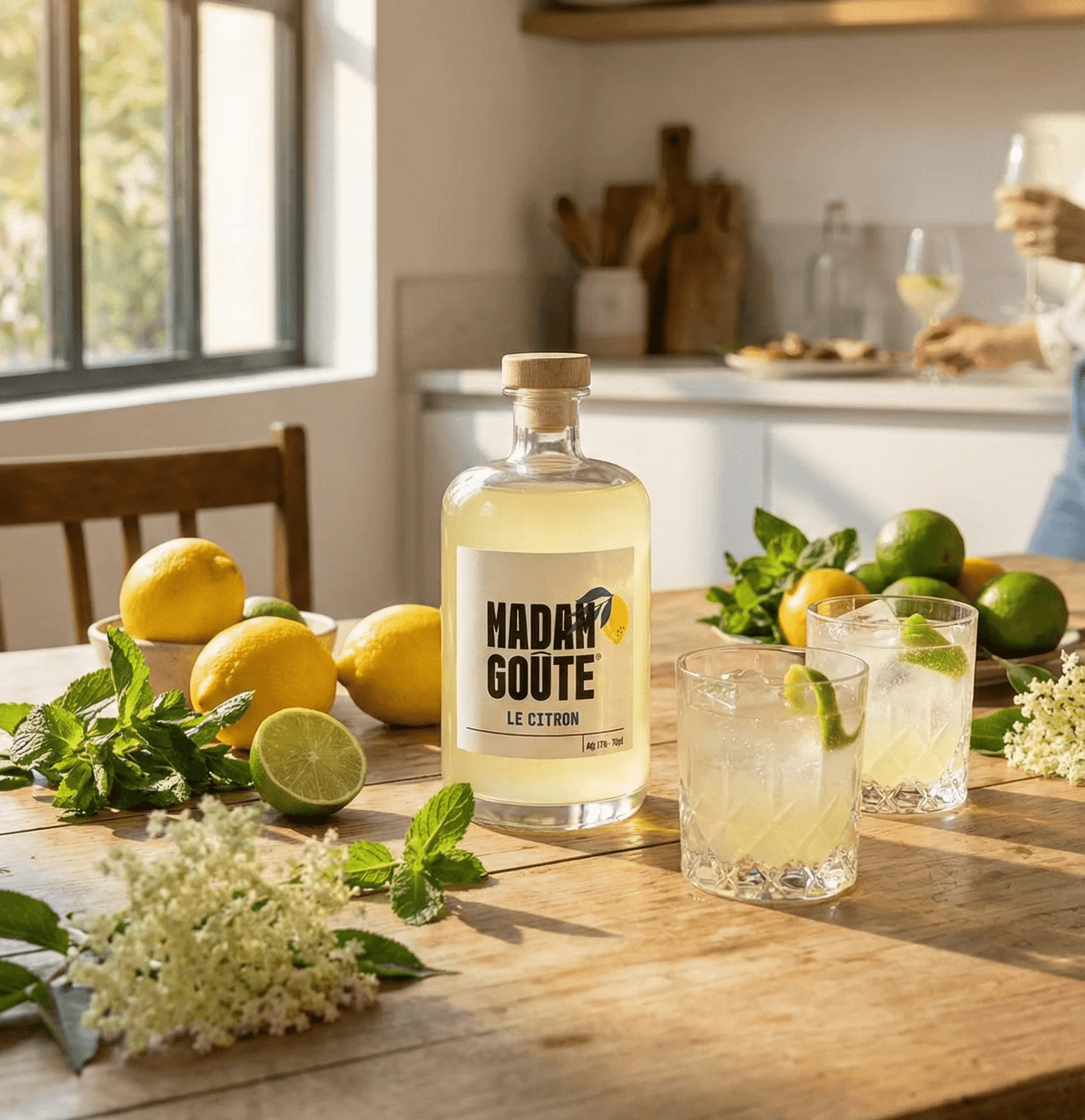 Liqueur de citron Madame Goute avec des agrumes frais et des cocktails sur une table rustique baignée de soleil.
