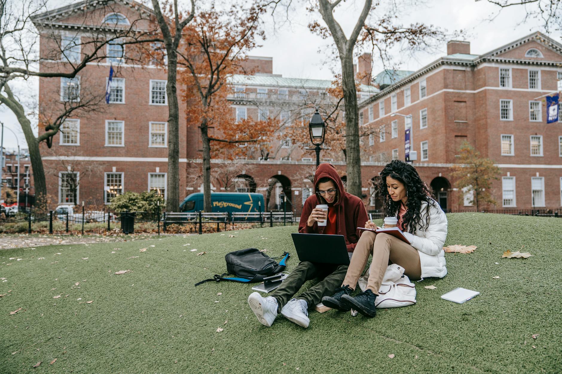 Two middle school students sitting shoulder-to-shoulder, focused on a single open textbook and discussing a problem.