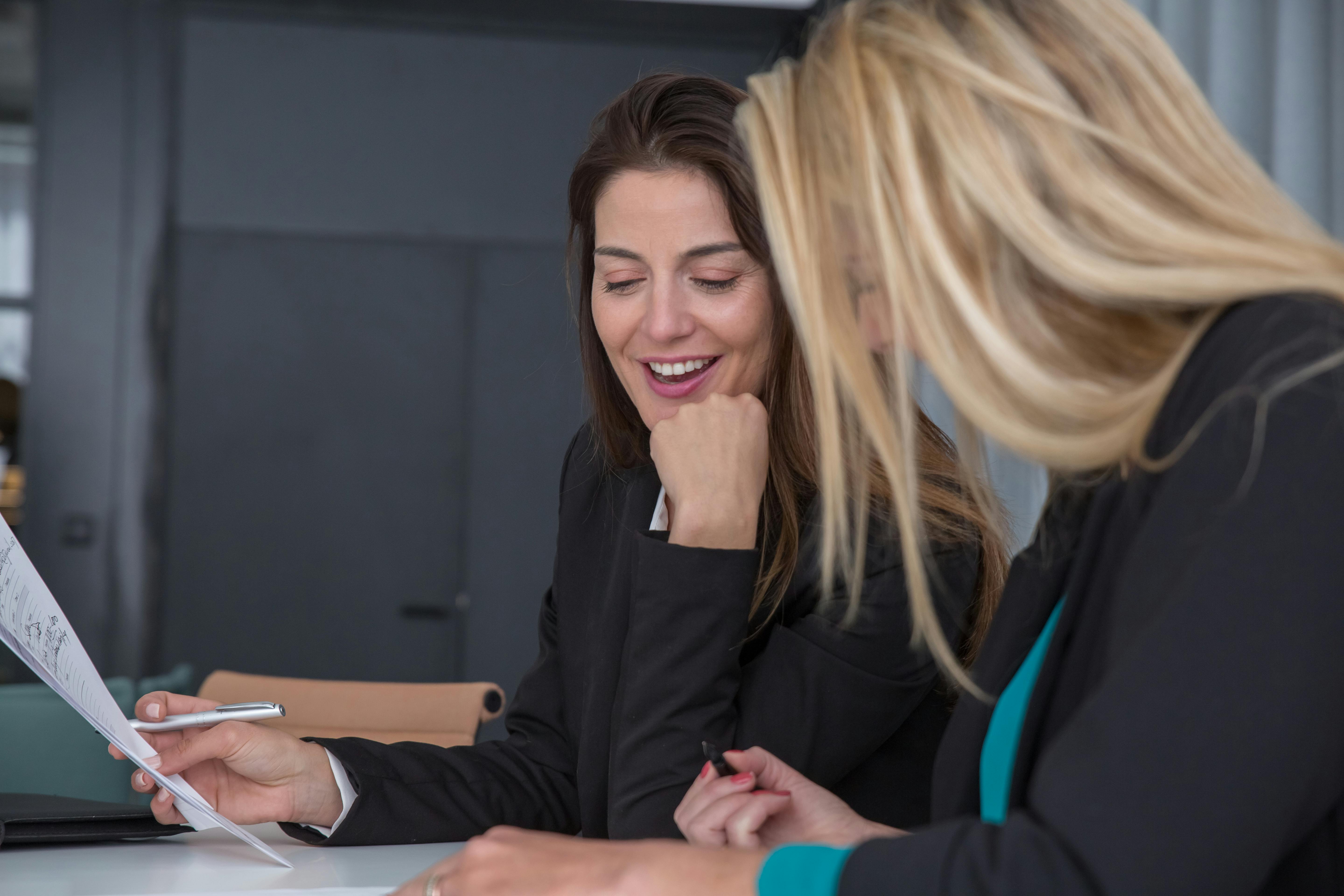 Colleghe sorridono analizzando un report: mentoring one to one e revisione