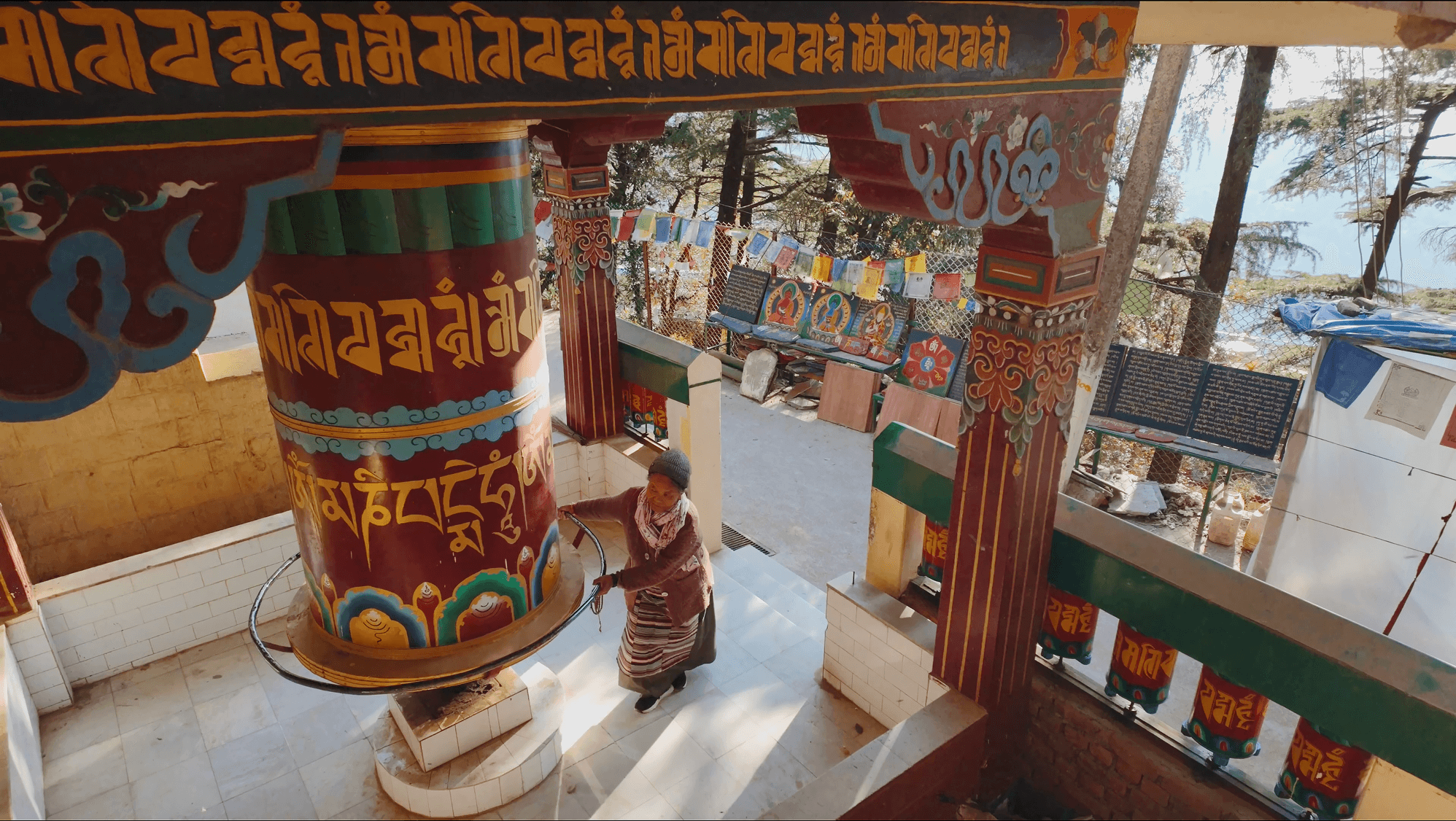 woman walking kora and turning drum with prayers, dharamshala, makleod ganj, tibetan culture, india retreat, spiritualism