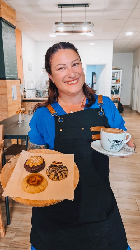 Cafe owner holding a tray of artisan cookies and a cup of coffee