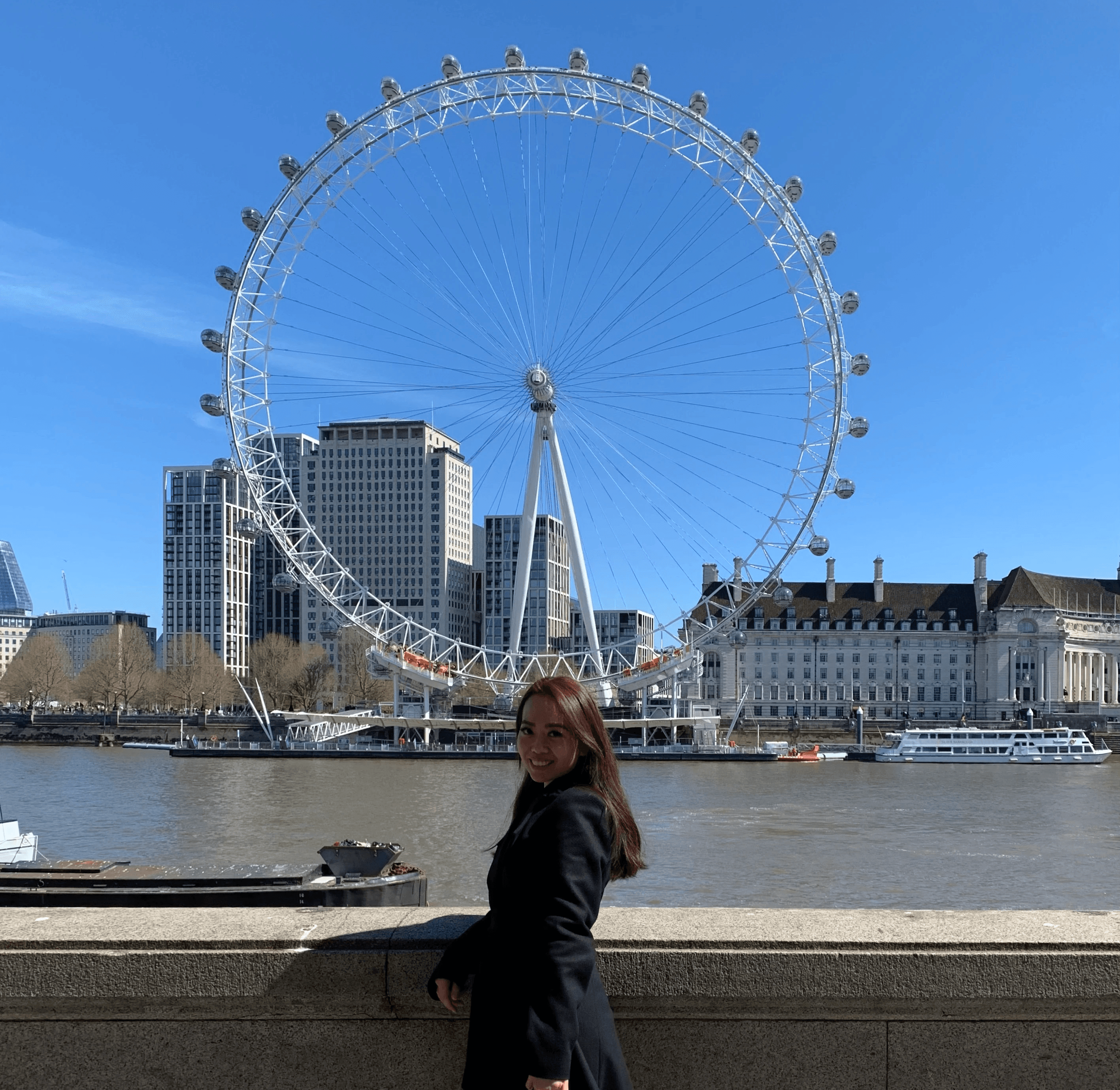 Smiling female therapist with short gray hair, wearing a brown top and a purple shawl, surrounded by a cozy background.