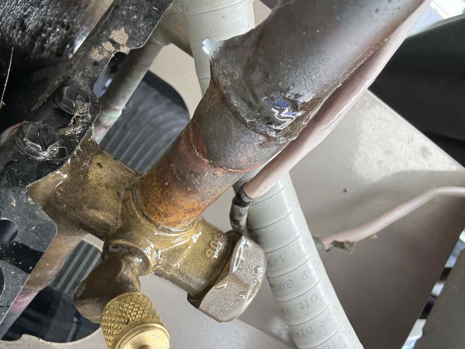 Oil residue at an AC suction line service cap, the sign of a refrigerant leak