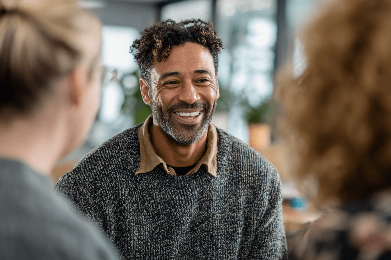 a home care agency owner, male, 40s, smiling and chatting with a group of caregivers in his caregiving agency.