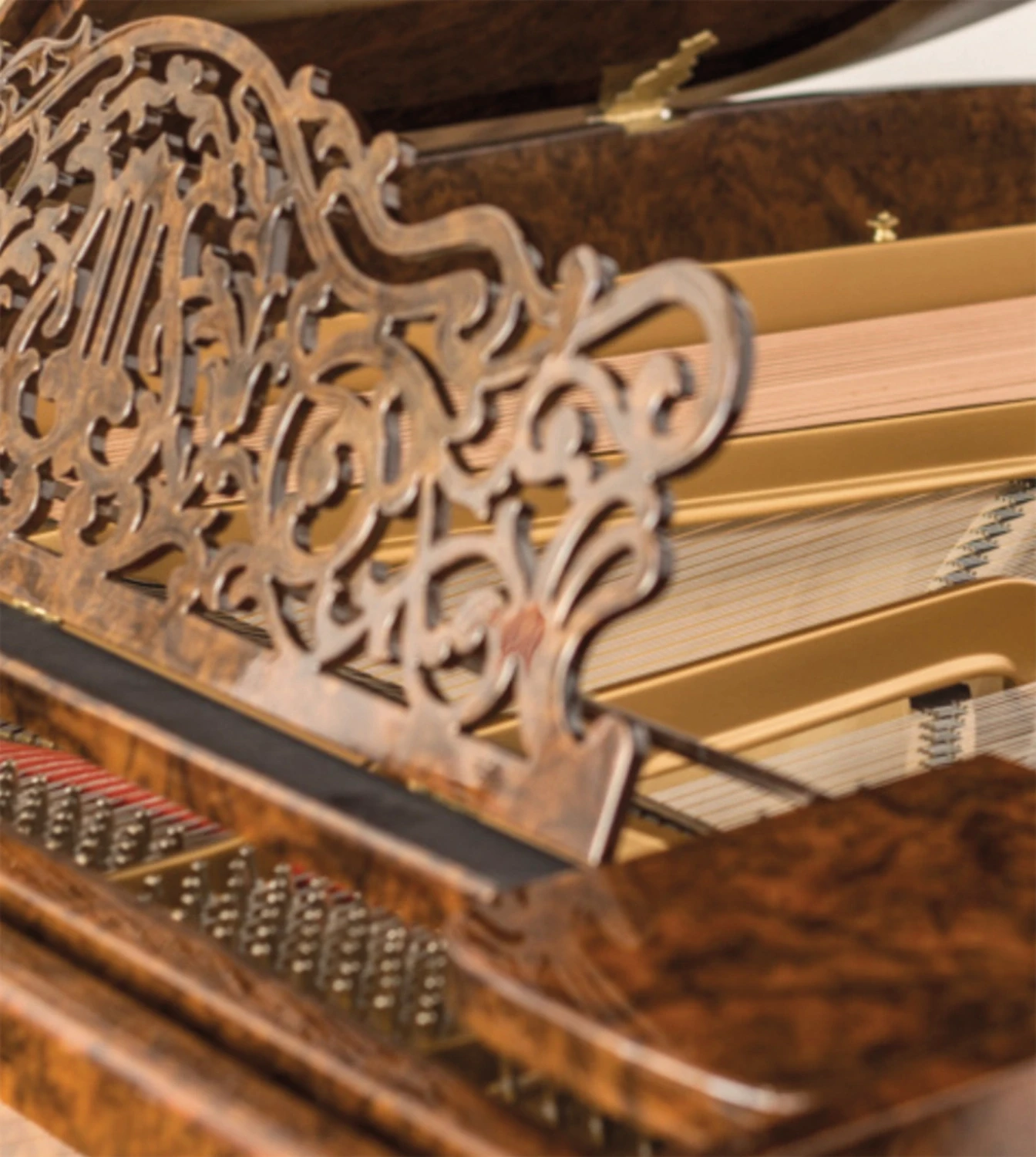 Close-up of the piano’s polished keyboard and rich burl wood veneer, showcasing expert craftsmanship.