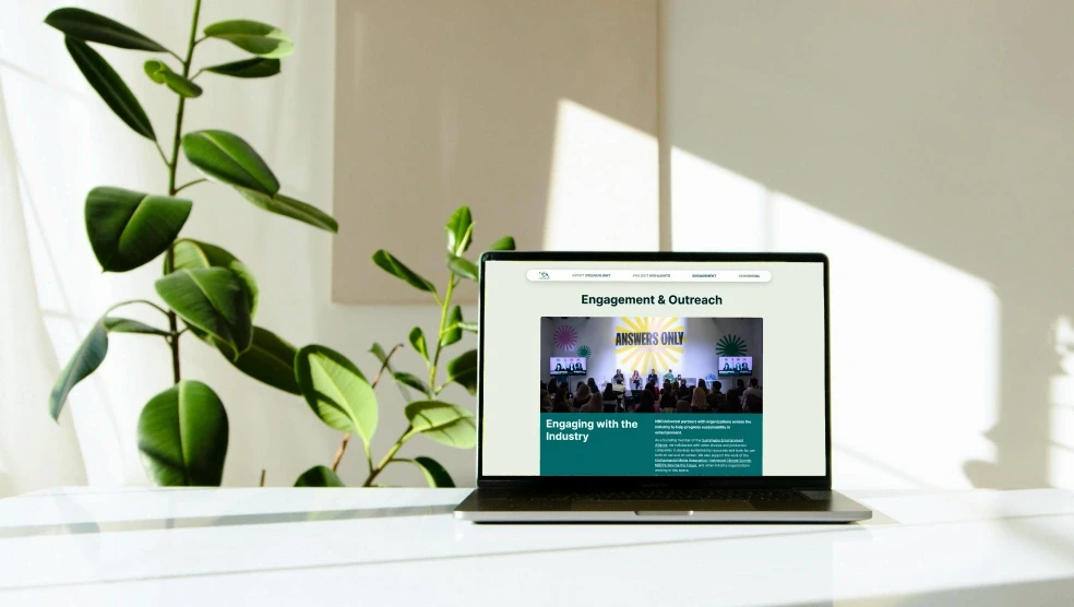Laptop mockup on a sunlit desk with a featured image card from the 'Engagement & Outreach' page on screen.