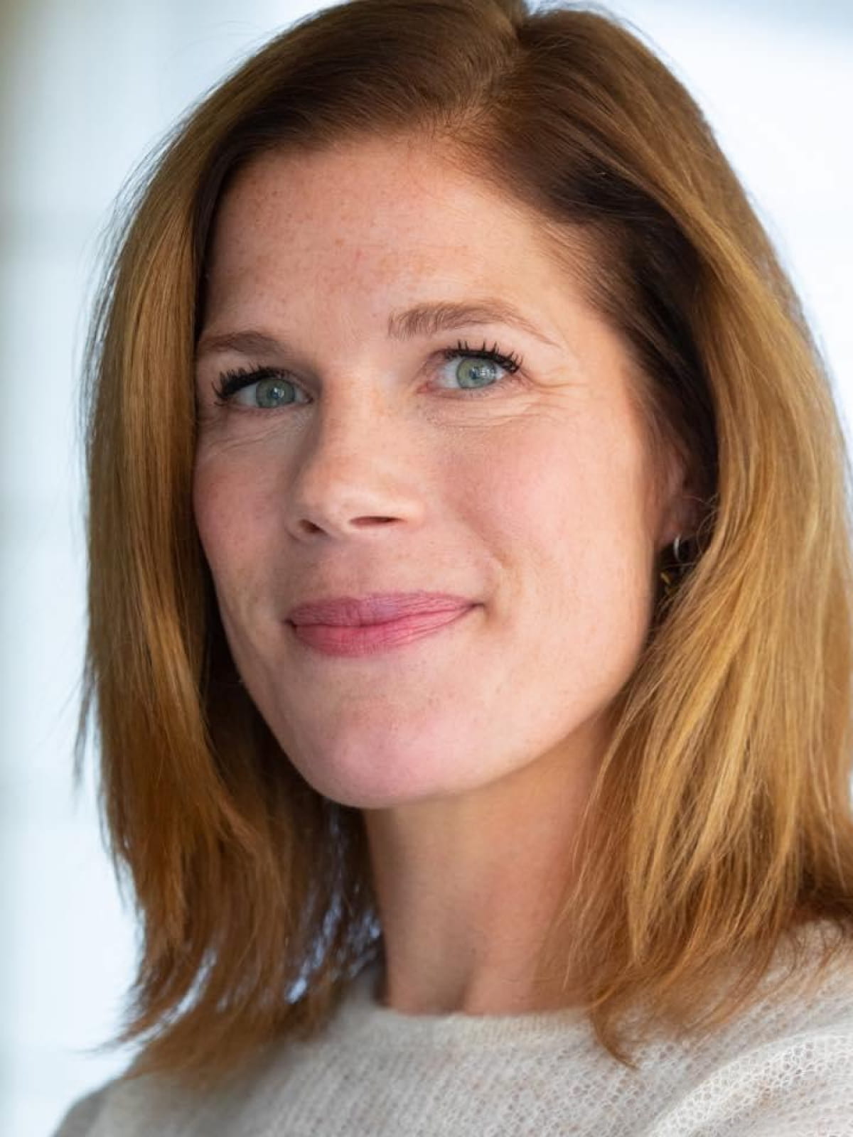 Portretfoto van Roos van der Burg, oprichter en CEO van SheVibes, lachend in een natuurlijke omgeving.
