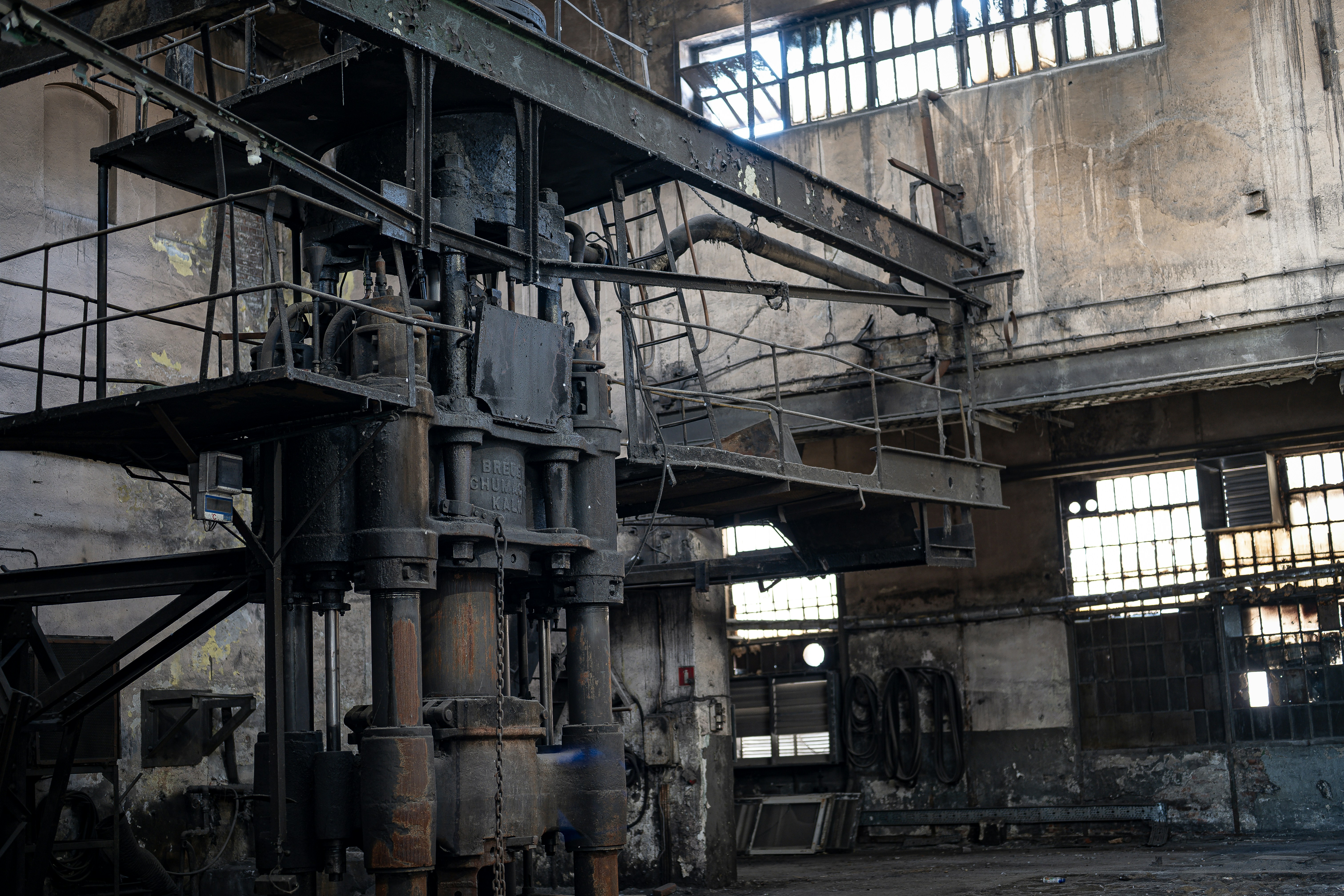 Old machinery sits in a derelict industrial building.