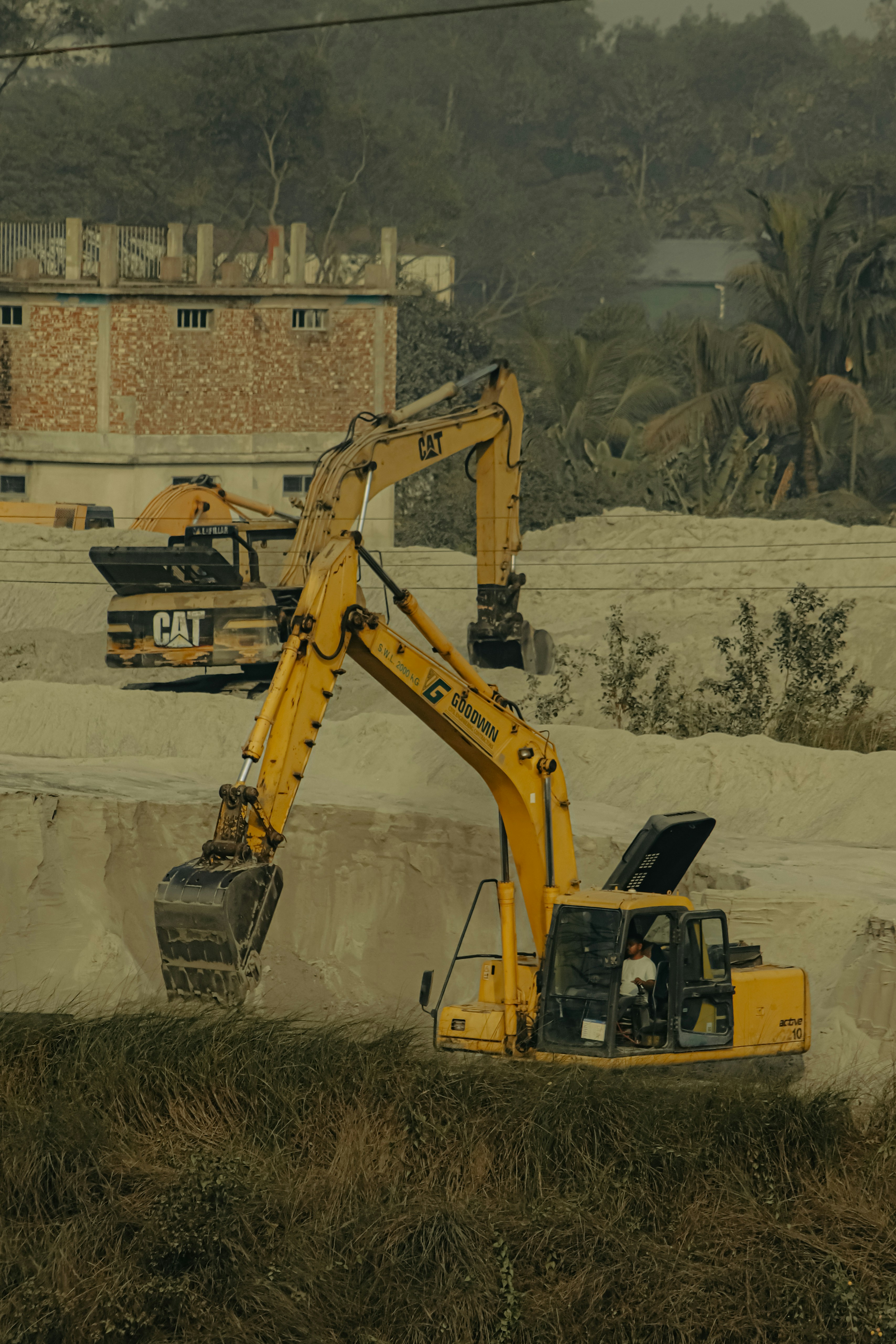 a yellow excavator sitting on top of a pile of dirt