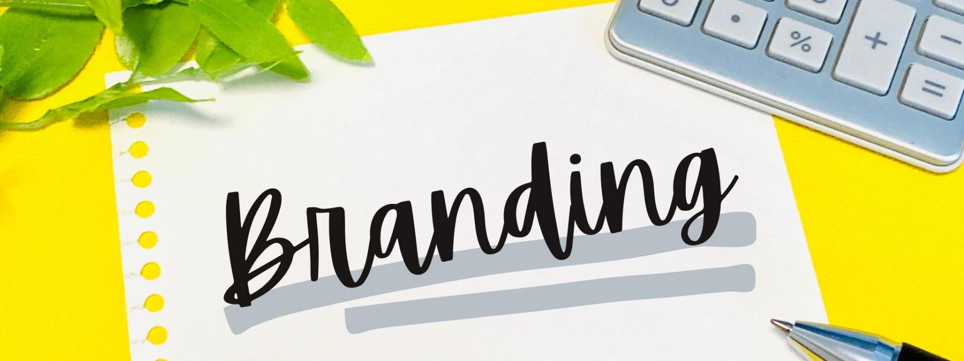 黄色の背景に置かれた白い紙に『Branding』と書かれたメモと文房具のイメージ