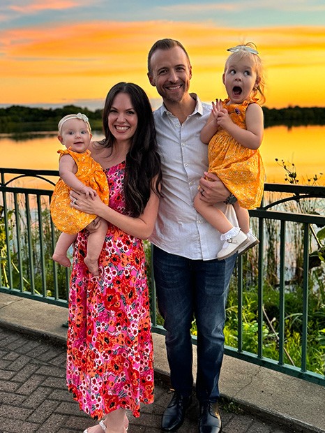 Family photo of the founders and their daughter with a sunset backdrop.