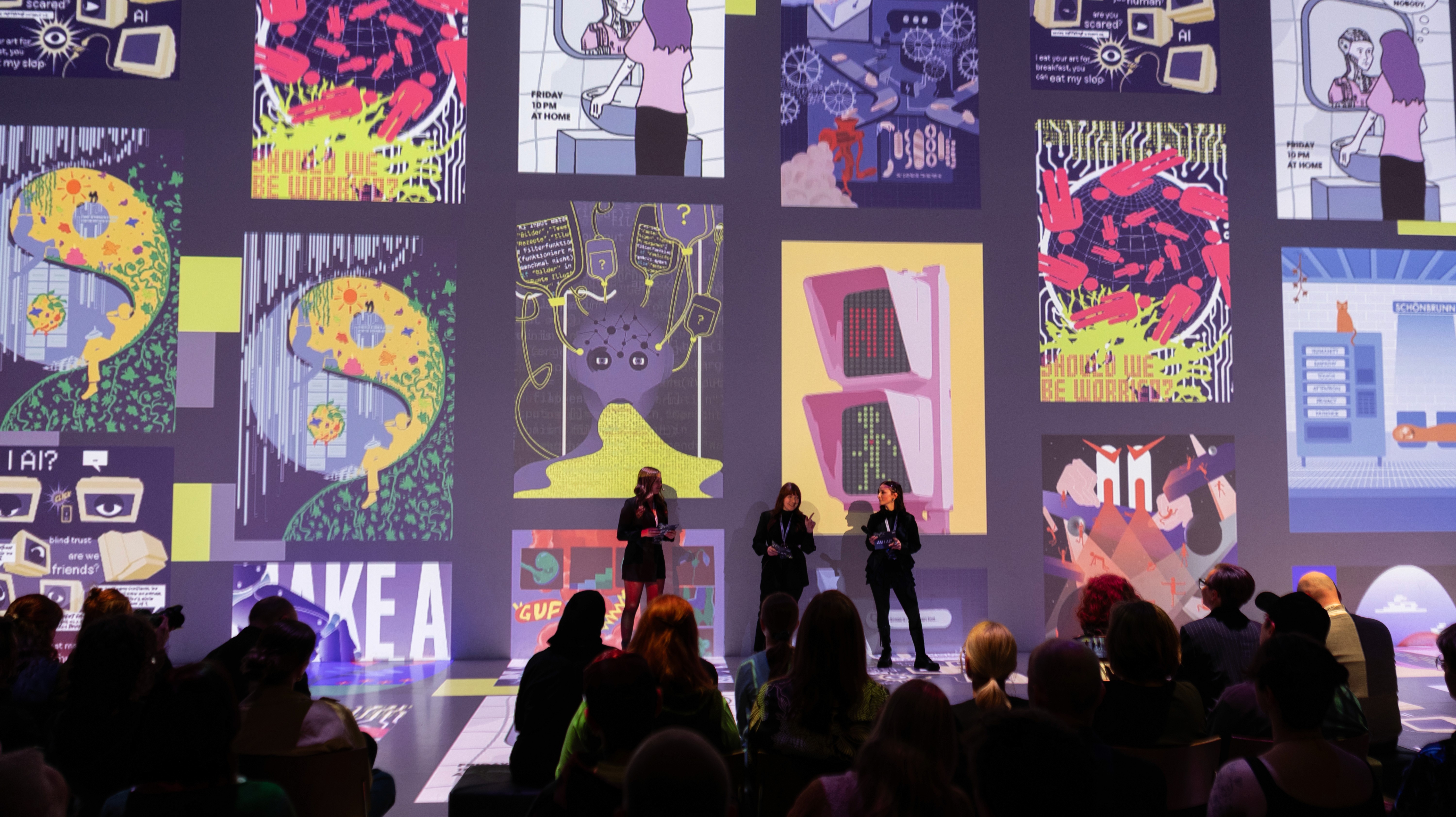 A laptop with colorful designs displayed on the screen, with people chatting and working in the background.