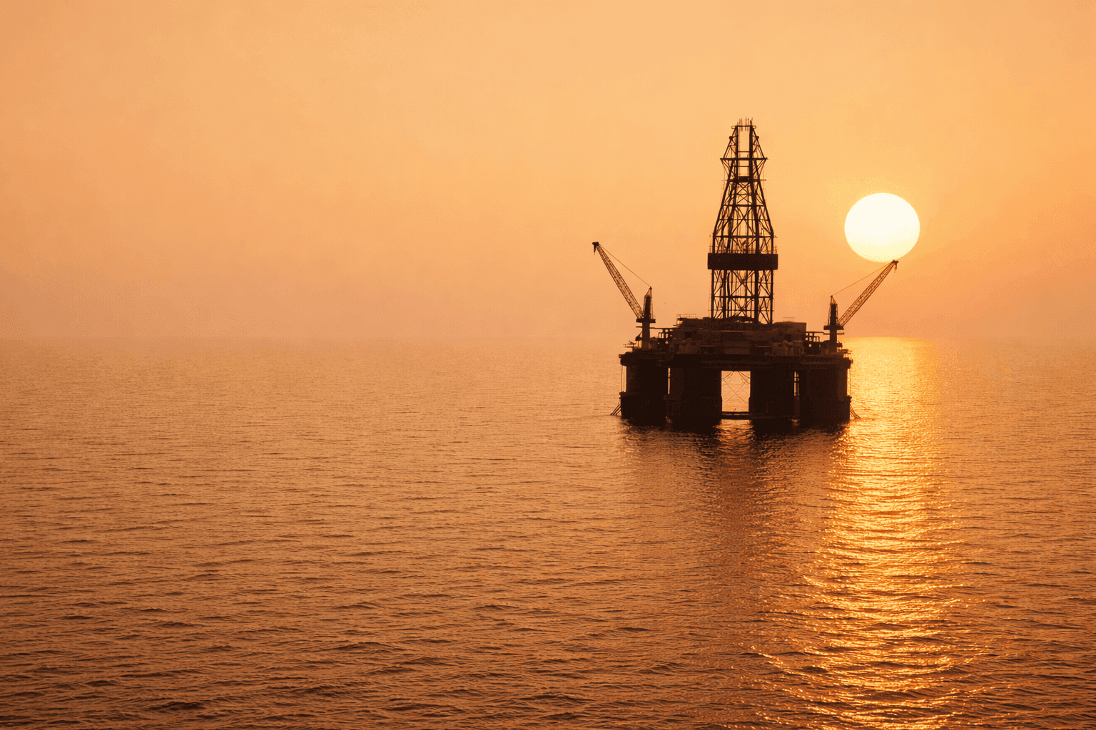 Image of an offshore oil rig at sunset