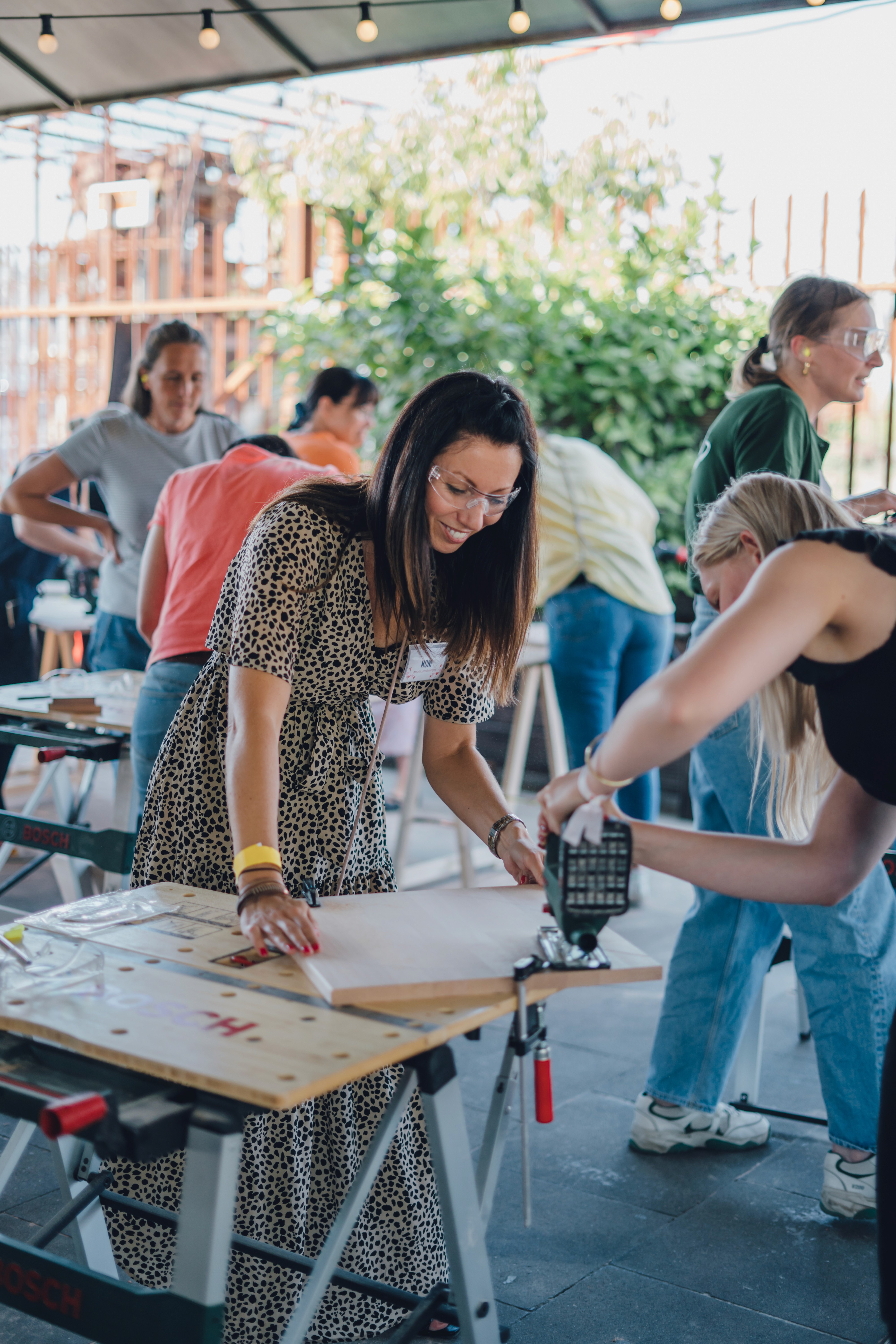 Teilnehmerin bearbeitet Holzplatten mit Werkzeugen beim Workshop mit Bosch.