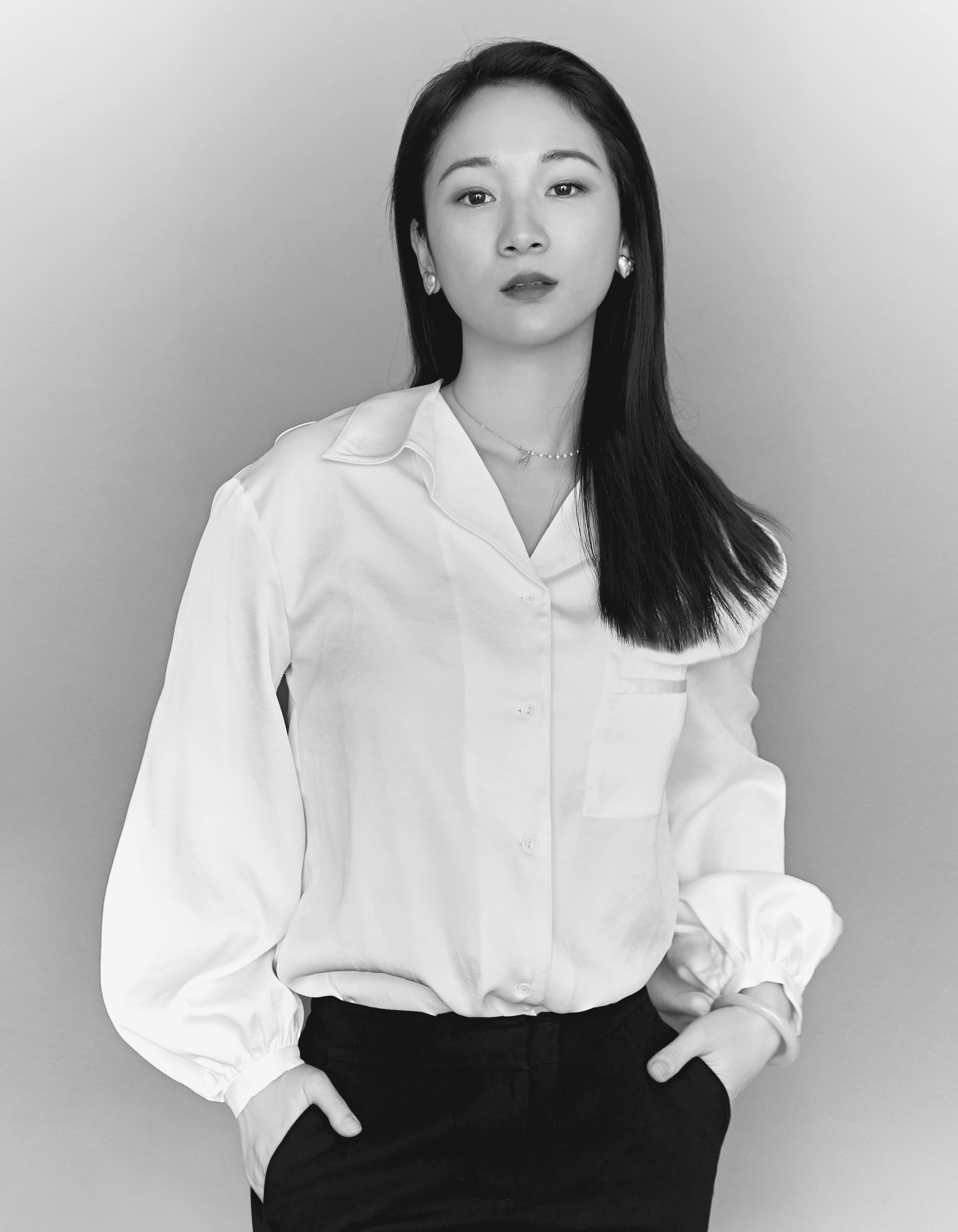 A thoughtful young person with dark hair gazes to the side, captured in soft black and white lighting.