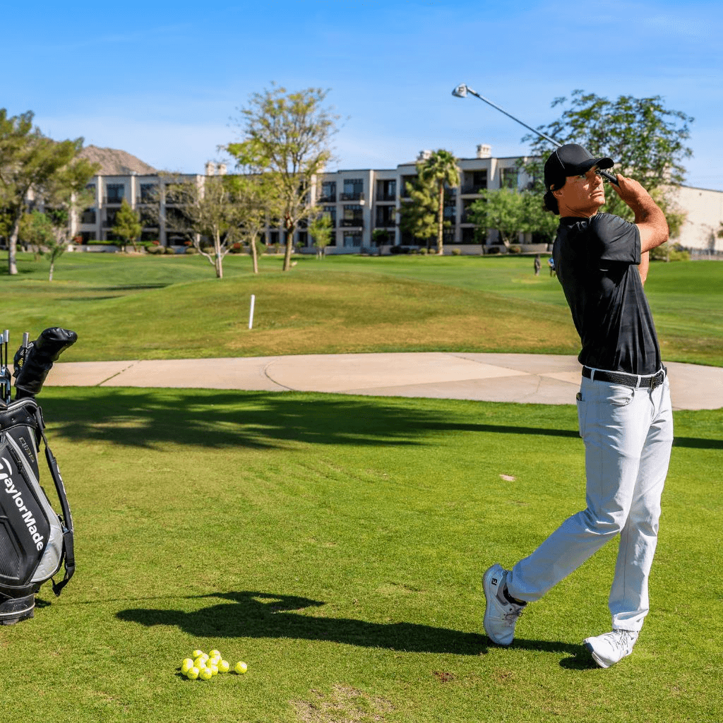 Golfer finishing a full swing on the practice area at Arizona Biltmore Golf Club, Phoenix