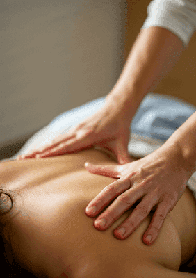 Zbliżenie na ręce fizjoterapełty masującego plecy kobiety