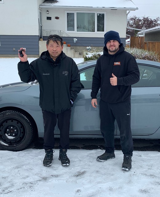 Customer holding a car key next to a CarKeyAction technician after on-site car key service in Calgary