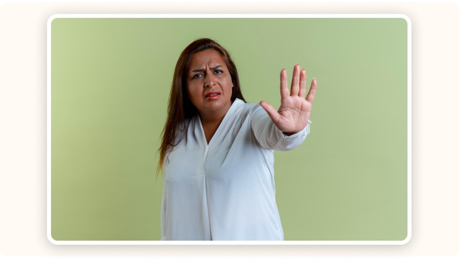 Woman in white shirt raising hand signaling stop with concerned expression