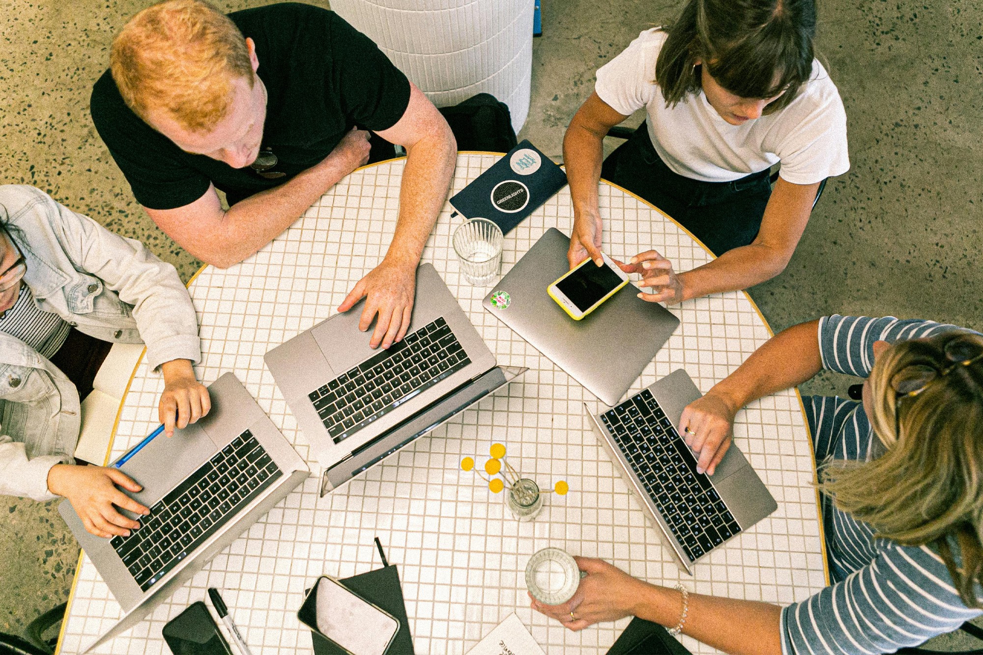 Overhead view of marketers collaborating with laptops, roundup of free AI tools for marketing to save time and improve campaigns.