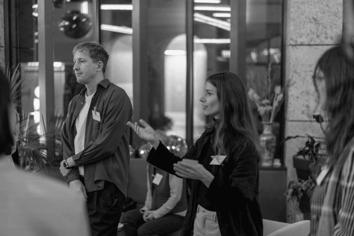 A woman speaking passionately, gesturing with her hands, while a man listens attentively during an indoor meeting. This interaction captures the essence of participative strategizing, highlighting the role of open dialogue in enhancing entrepreneurial capabilities.