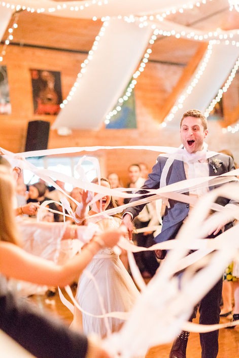 Groom wrapped in ribbons during a wedding celebration at Camp Lenox