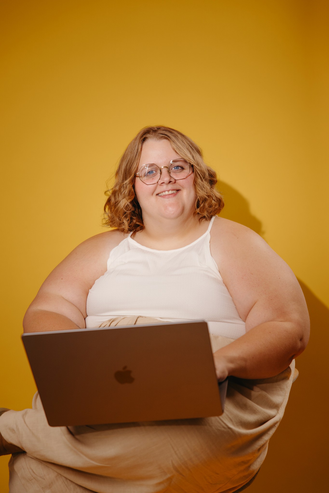 Headshot of Bayless with a laptop on a yellow background