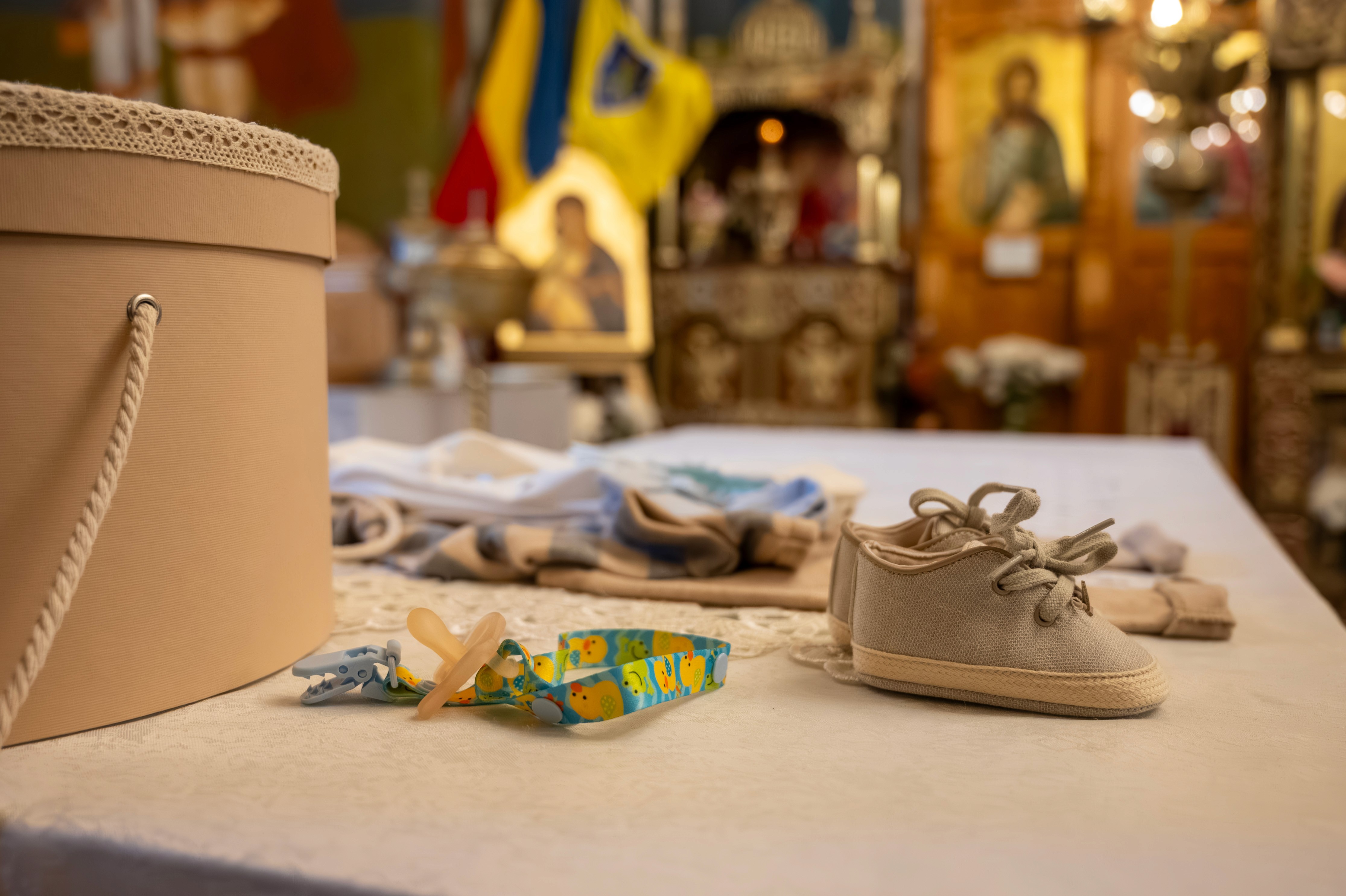 Trusou de botez, haine și accesorii pregătite pe masă — detaliu important al ceremoniei de botez.