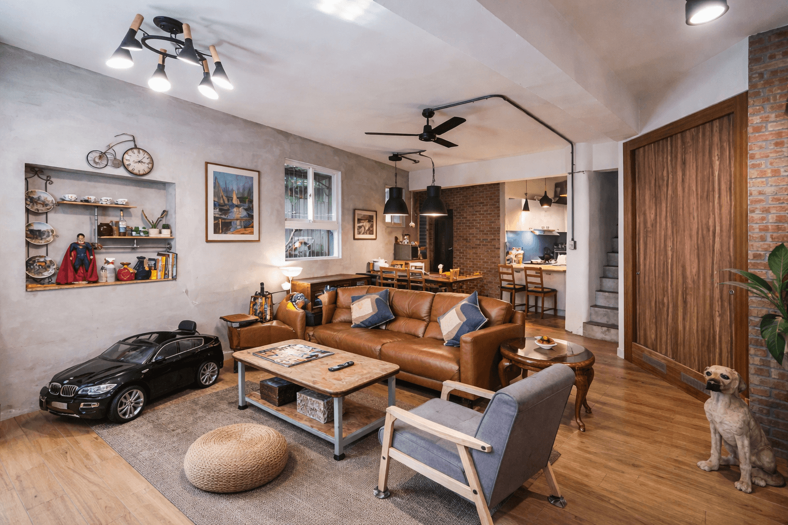 Living room with leather furniture, brick wall, and decorative bicycle. Includes a miniature car and a dog.