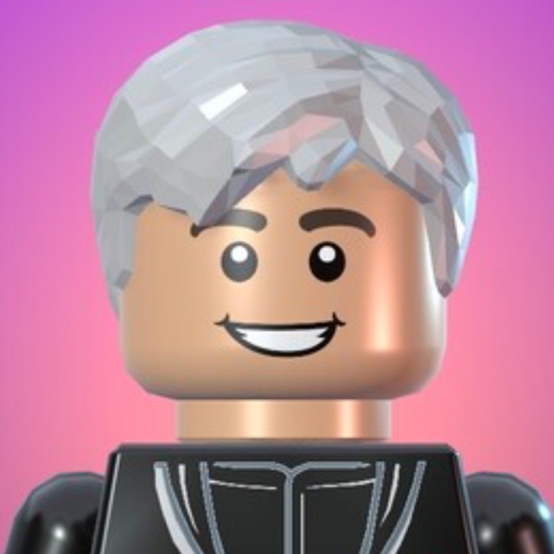 An image of the emagineer founder, Keira, but as a LEGO minifigure on a pink/purple gradient background. Keira has grey hair and is wearing a black shirt.