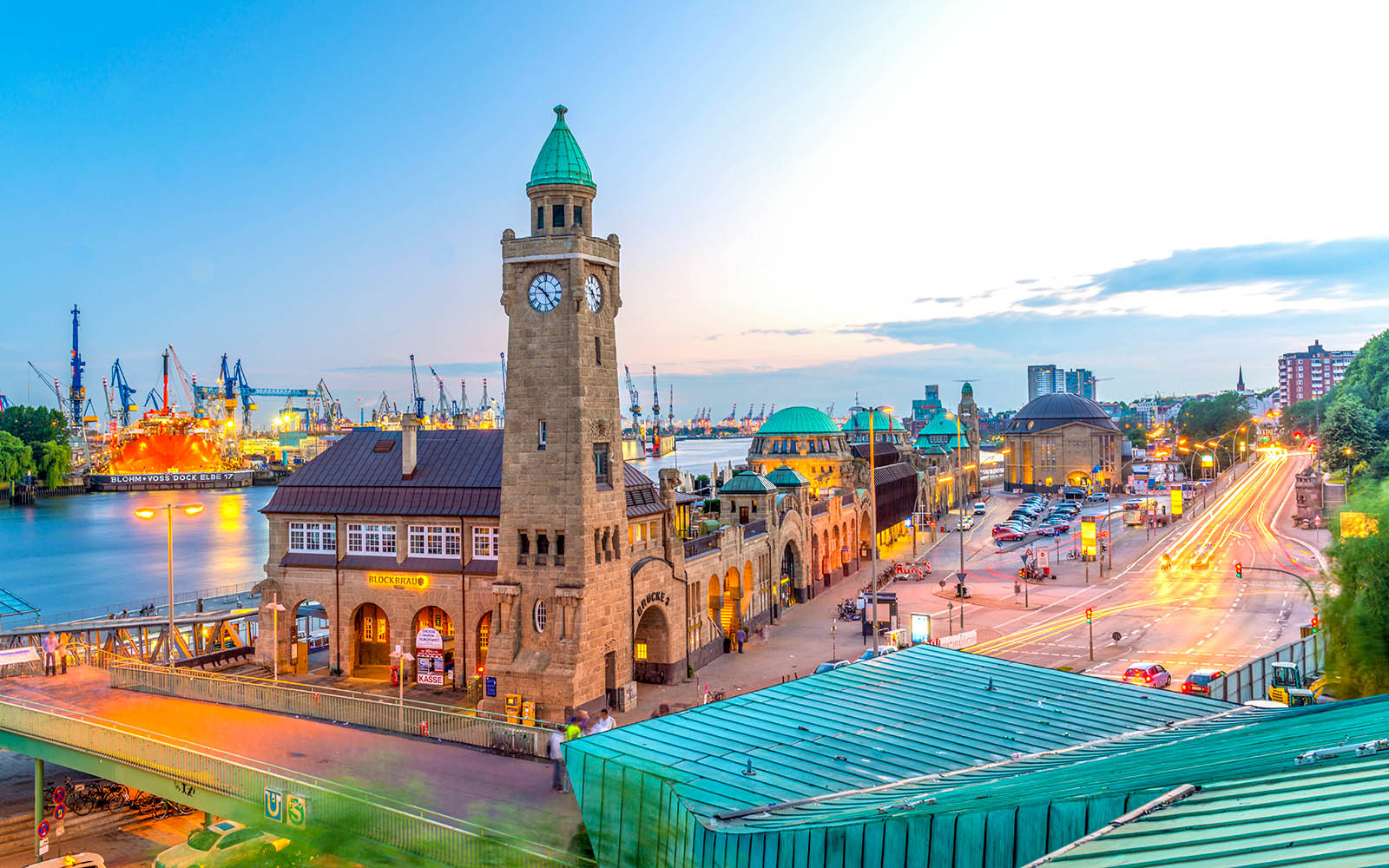 Widok na port w Hamburgu z zabytkową wieżą zegarową i tętniącym życiem nabrzeżem.