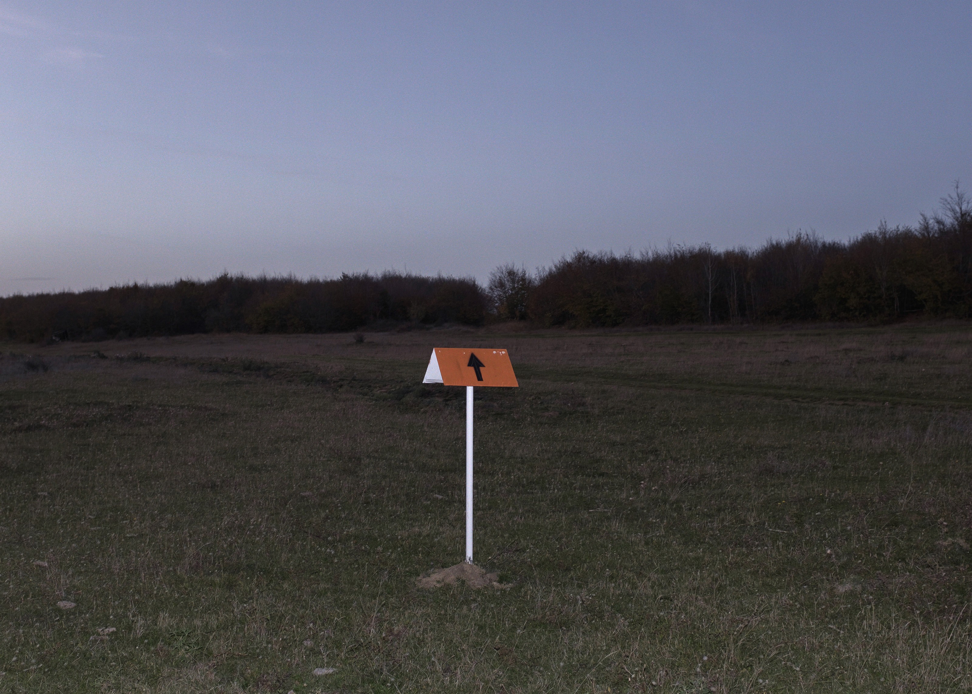 Orange border marker sign in an empty field