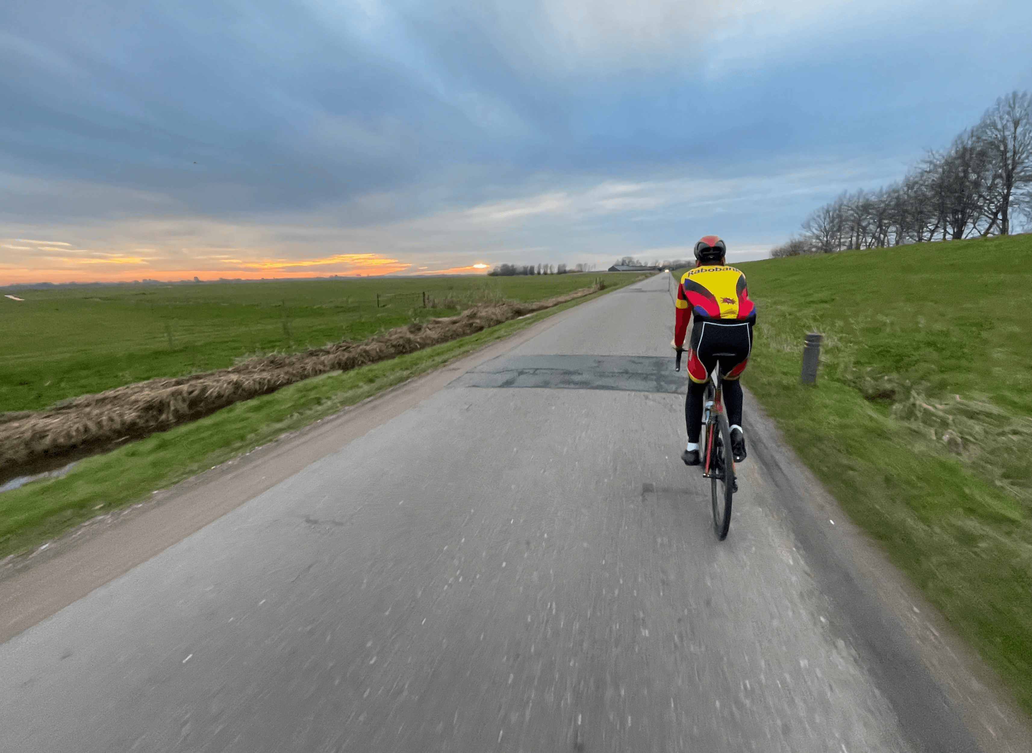 Cyclist riding on a road through fields.