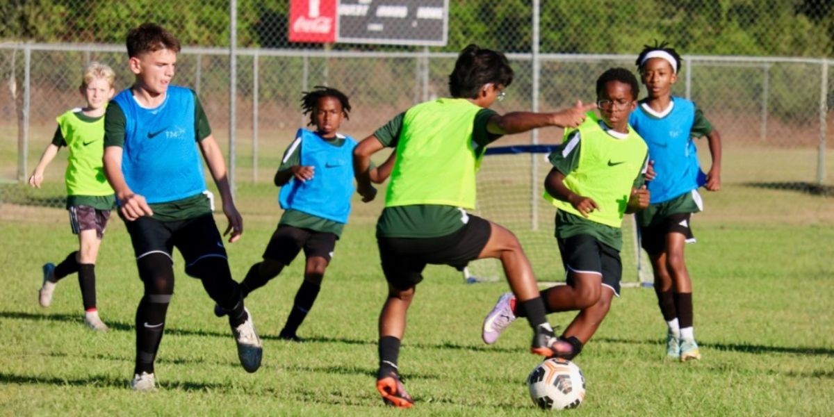 Young soccer players in green and blue jerseys participate in a TM17pro camp, focused on skill development and teamwork.