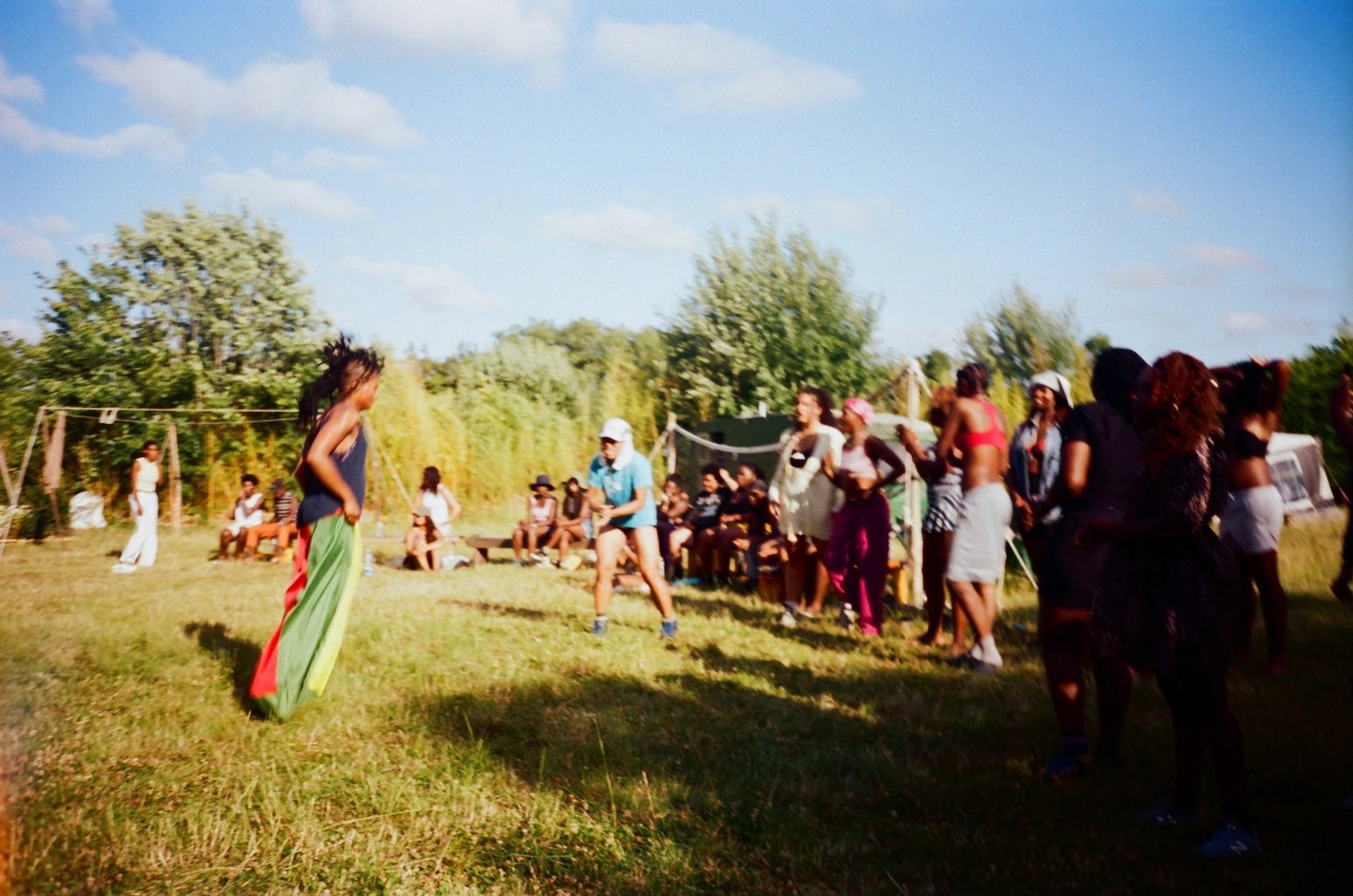 A person racing in a sack race surrounded by other people cheering her on