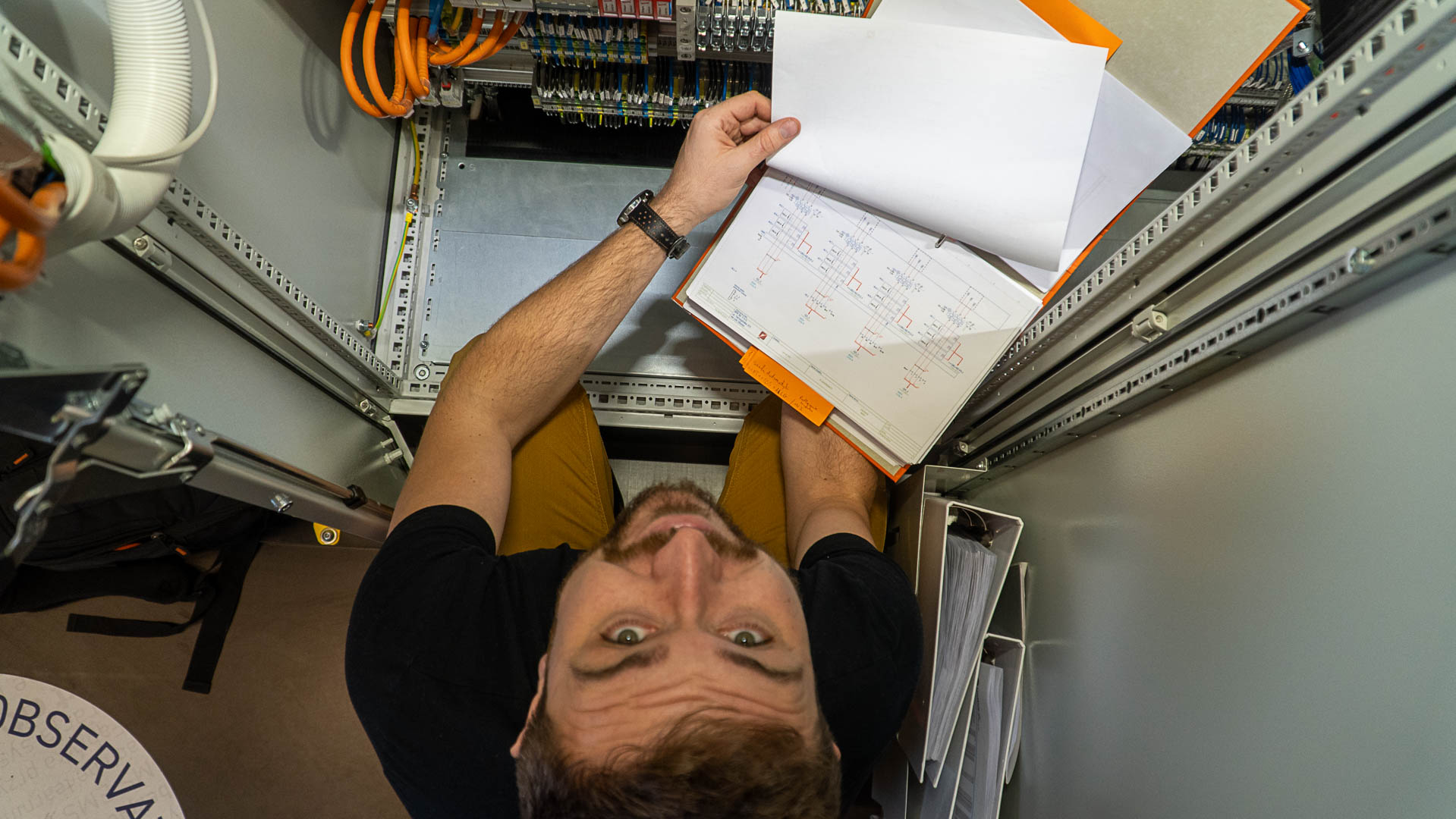 Instruktorius analizuoja schemas prie valdymo spintos