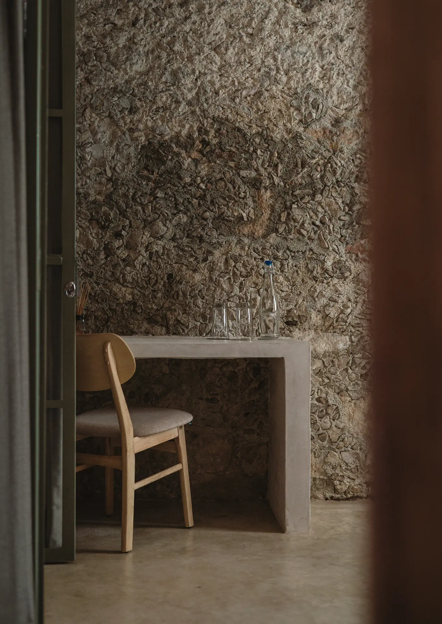 Villa Petite Comite - Detalle de mesa de concreto, silla, vasos, muro de piedra