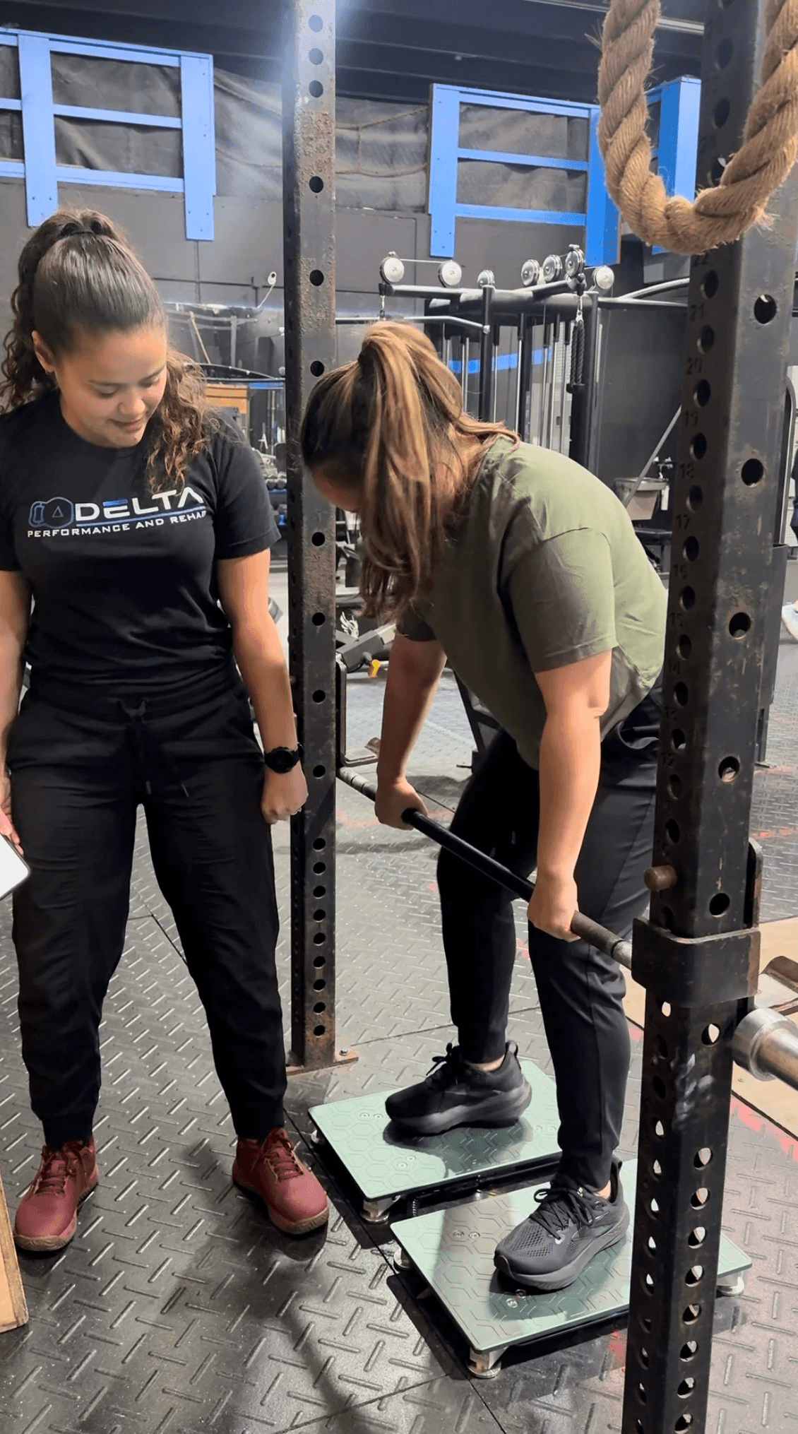 Close-up of kettlebells and a medicine ball on a black gym floor during a functional fitness session—emphasizing strength training, rehab tools, and athletic conditioning.