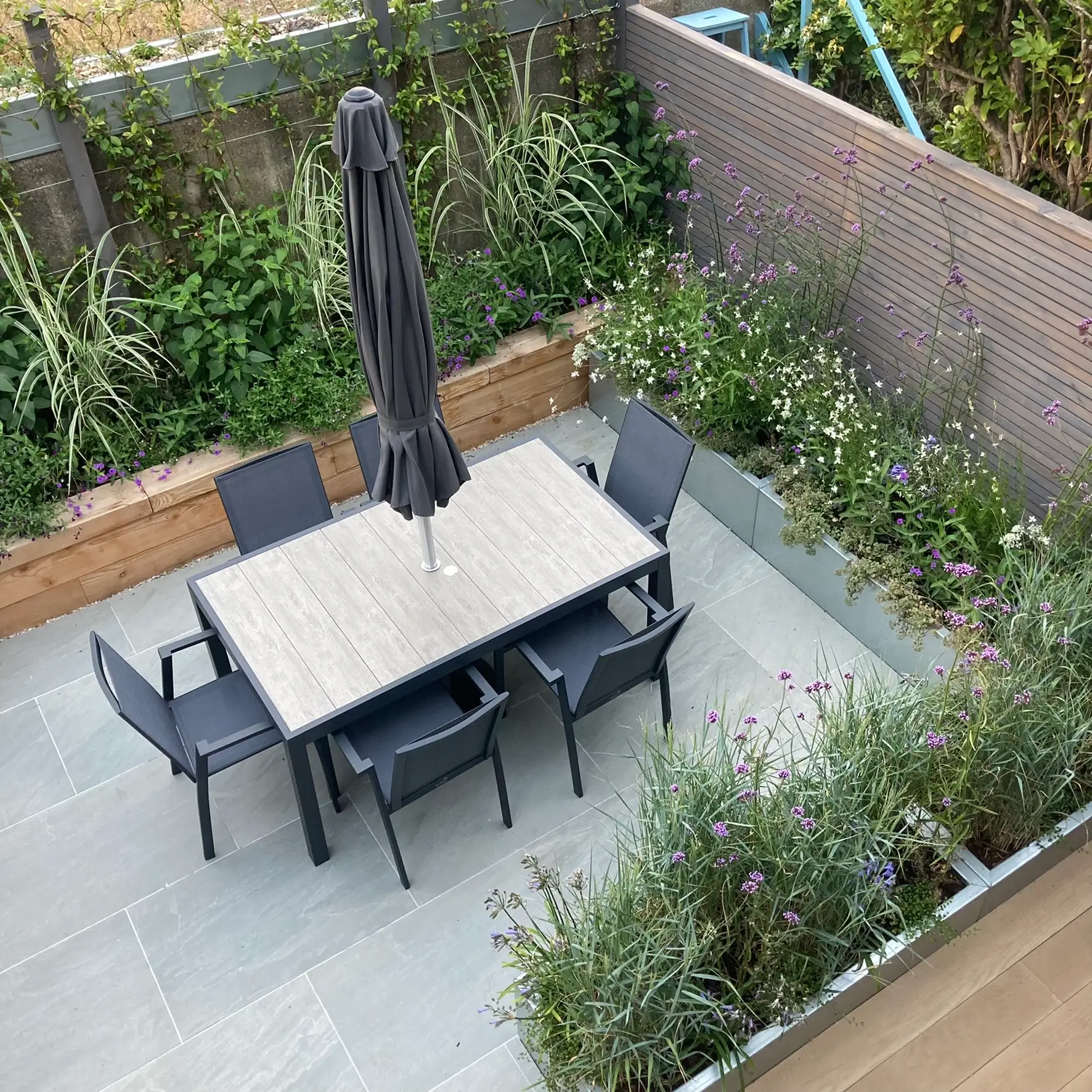 Aerial view of a cozy outdoor dining area with a table, chairs, and surrounding greenery.