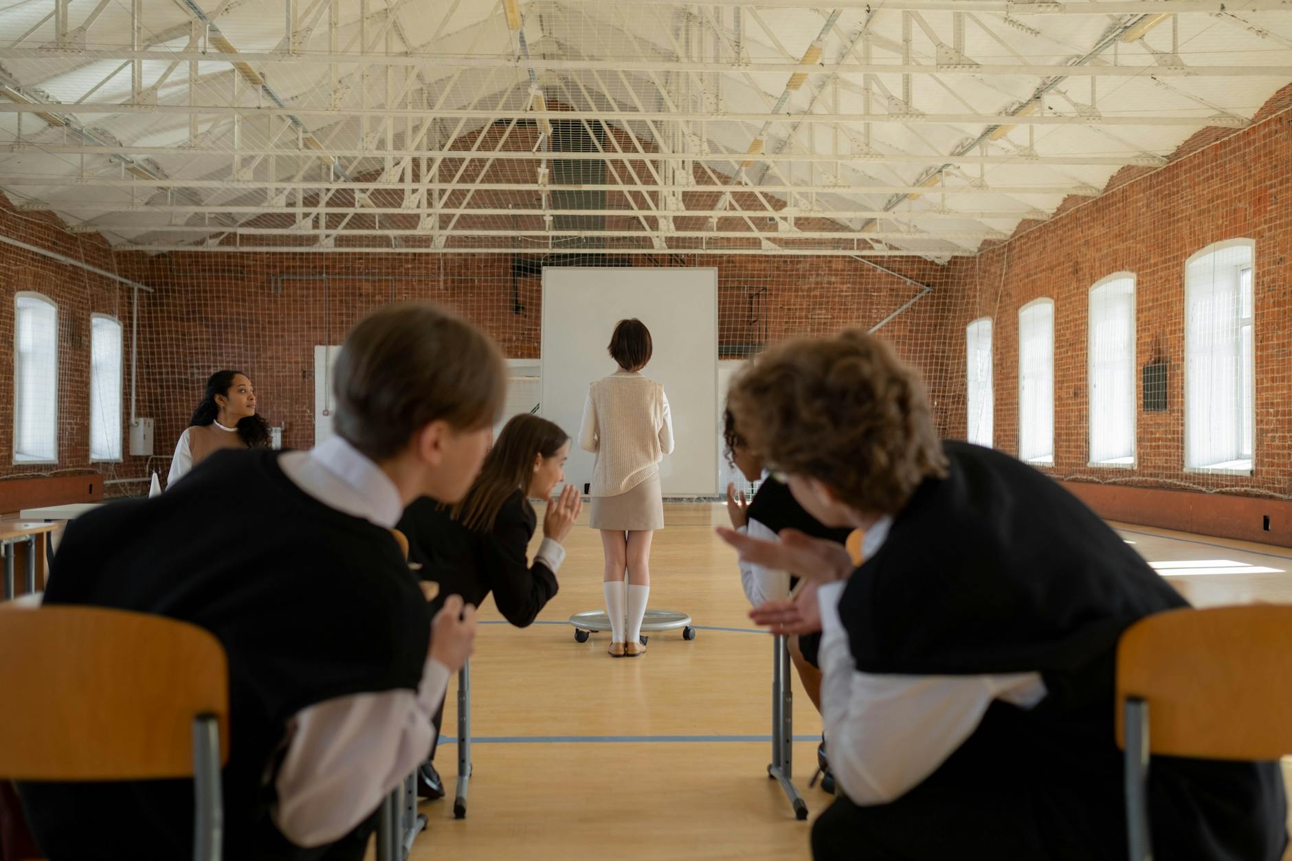 A teacher standing at a whiteboard explaining the think pair share strategy to an attentive class.
