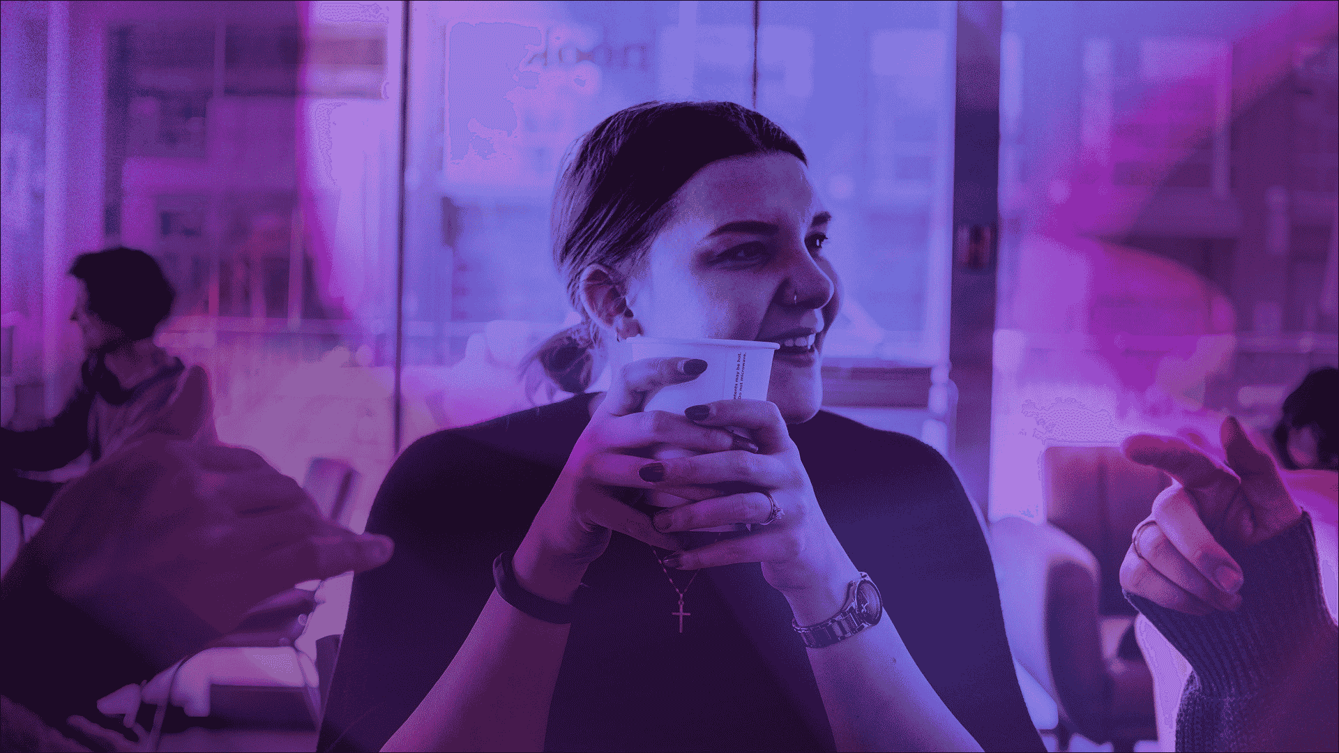A woman drinks a coffee while talking to friends